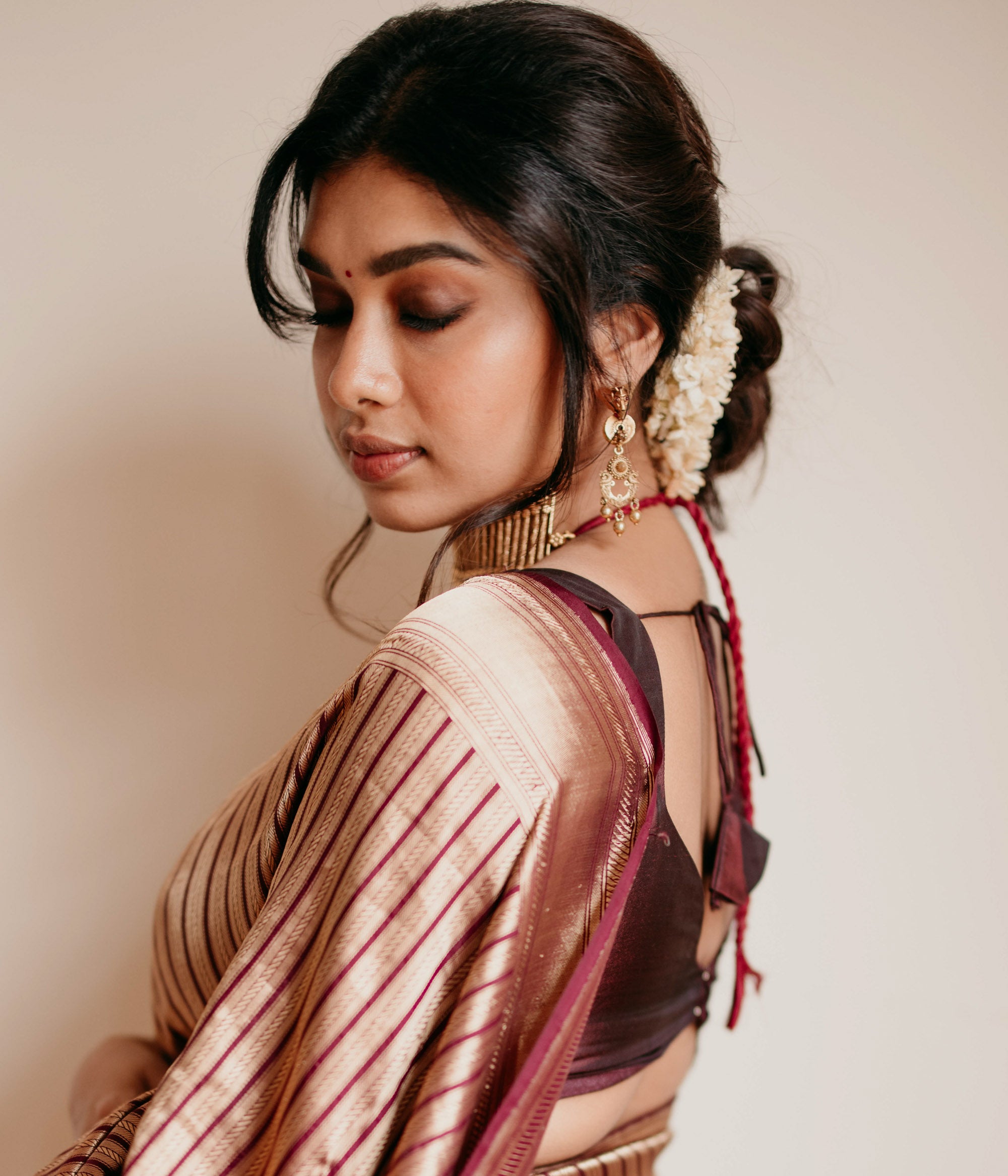 Gold tribal earrings with dangling design and Red Spinal Stones, styled with traditional jasmine hairdo.