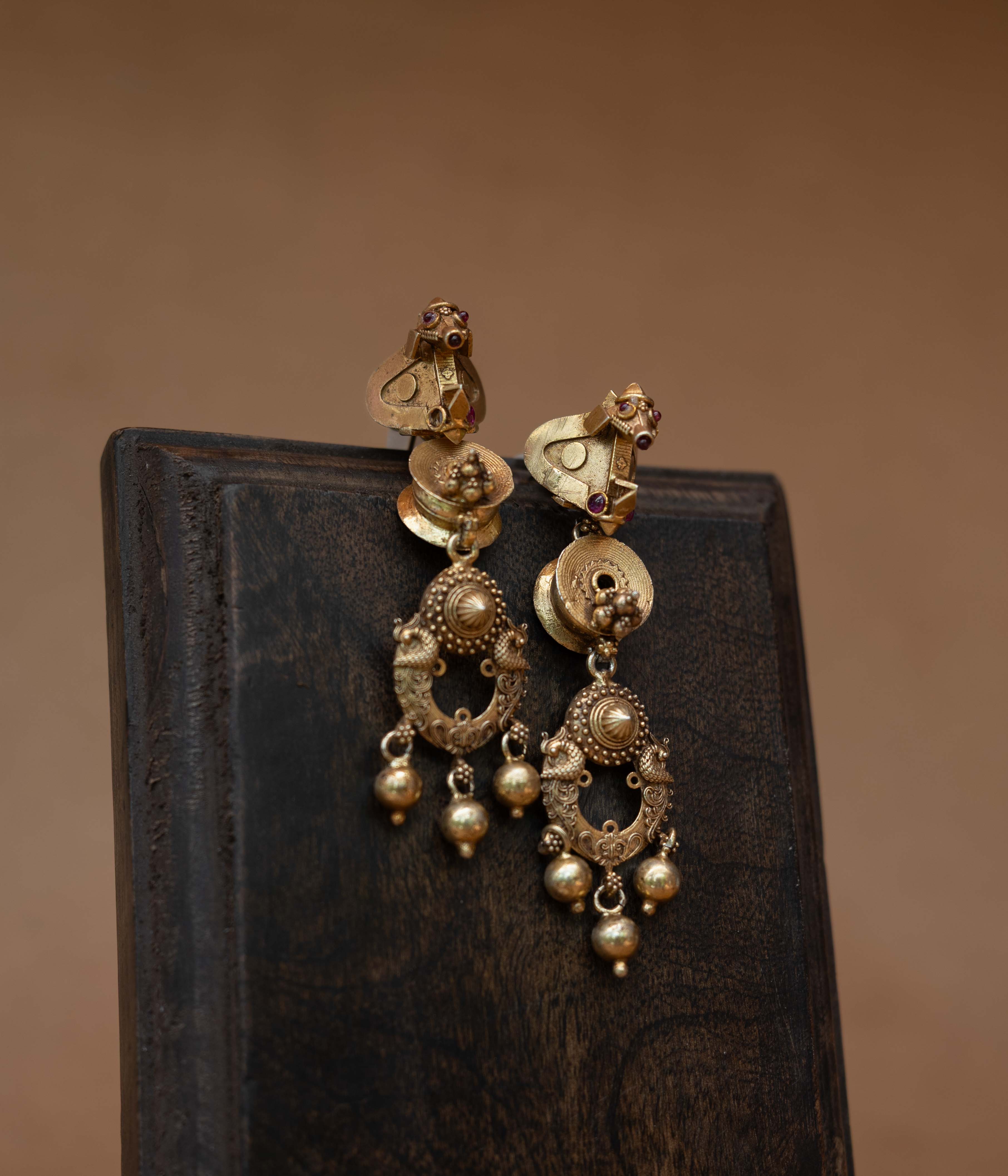Gold tribal earrings with dangling design and Red Spinal Stones, styled with traditional jasmine hairdo.