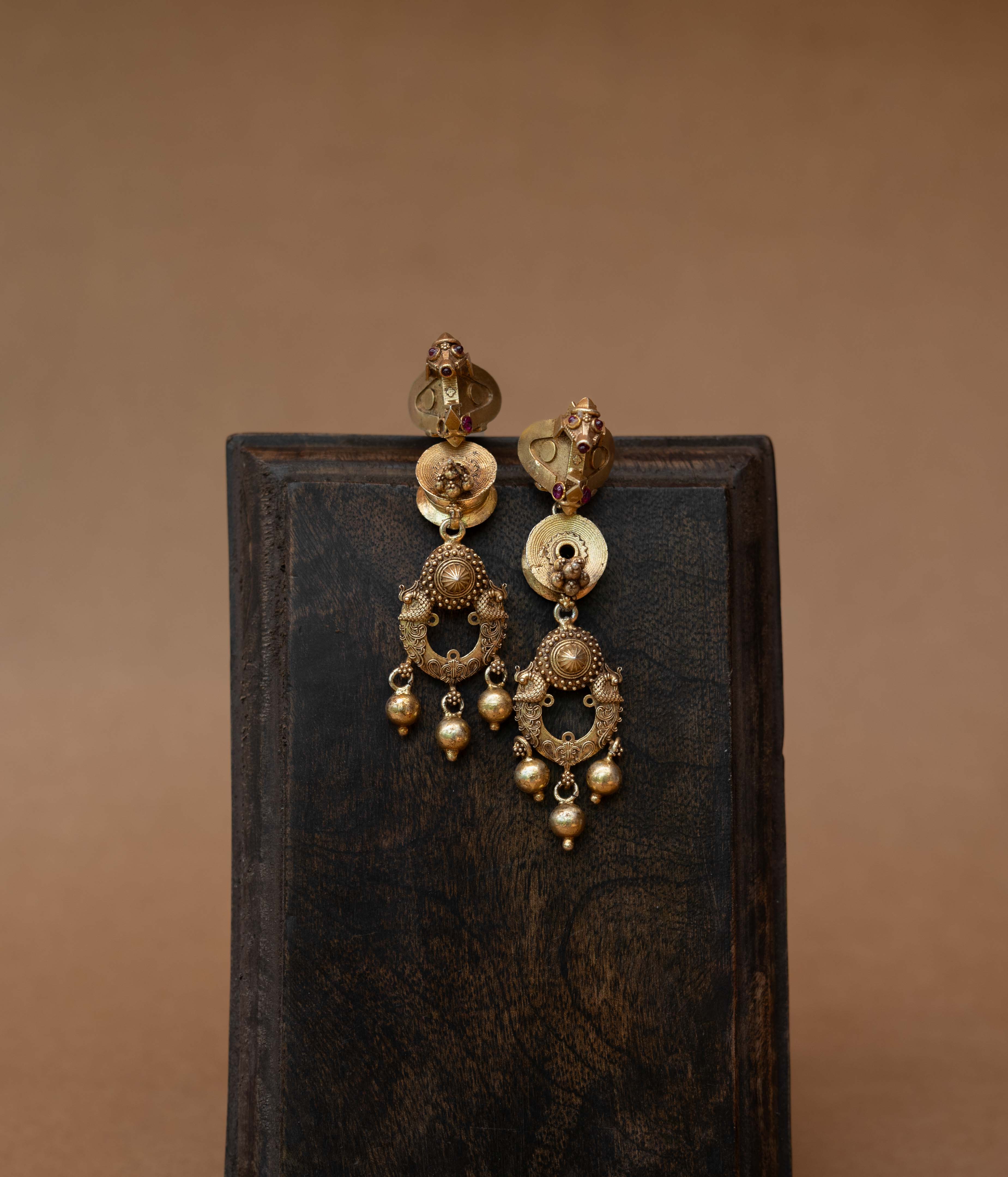 Gold tribal earrings with dangling design and Red Spinal Stones, styled with traditional jasmine hairdo.