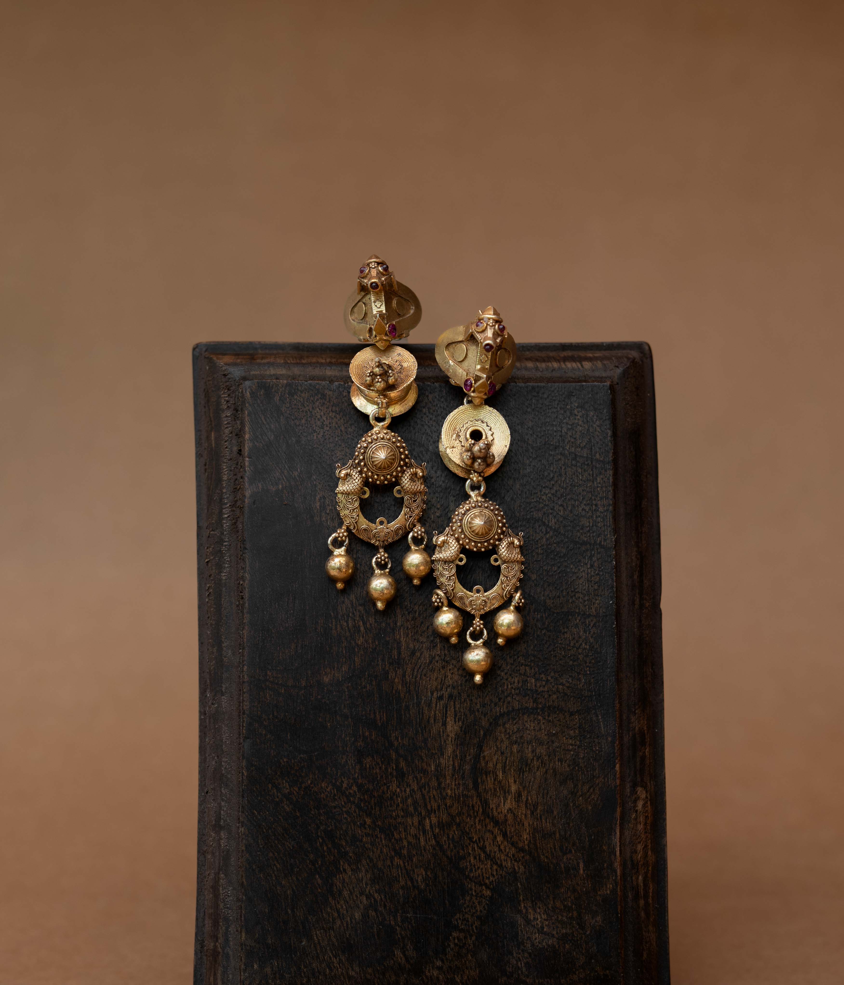 Gold tribal earrings with dangling design and Red Spinal Stones, styled with traditional jasmine hairdo.