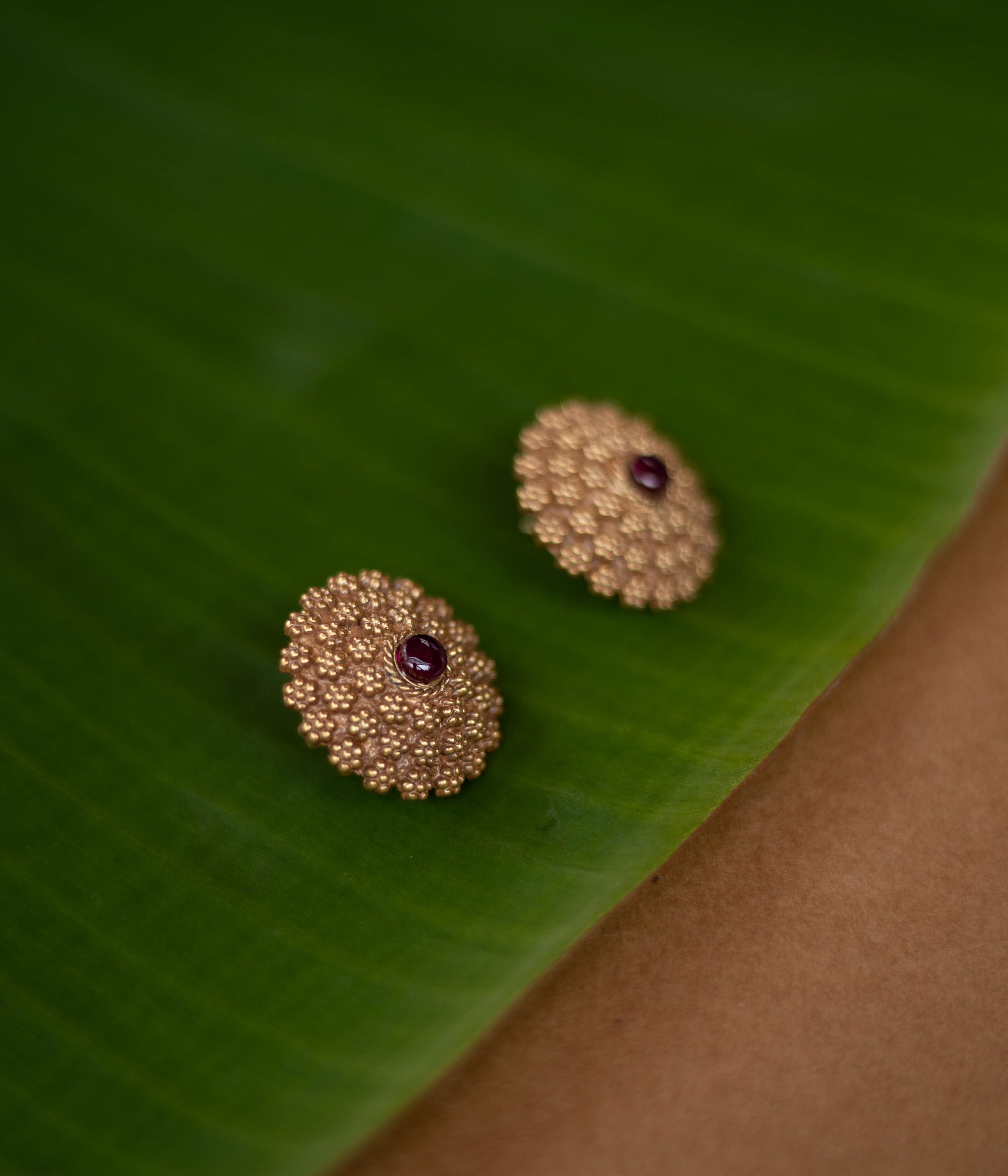 Thara earrings featuring red spinel stones in a floral crest design, made of 92.5 sterling silver with 22ct gold plating.