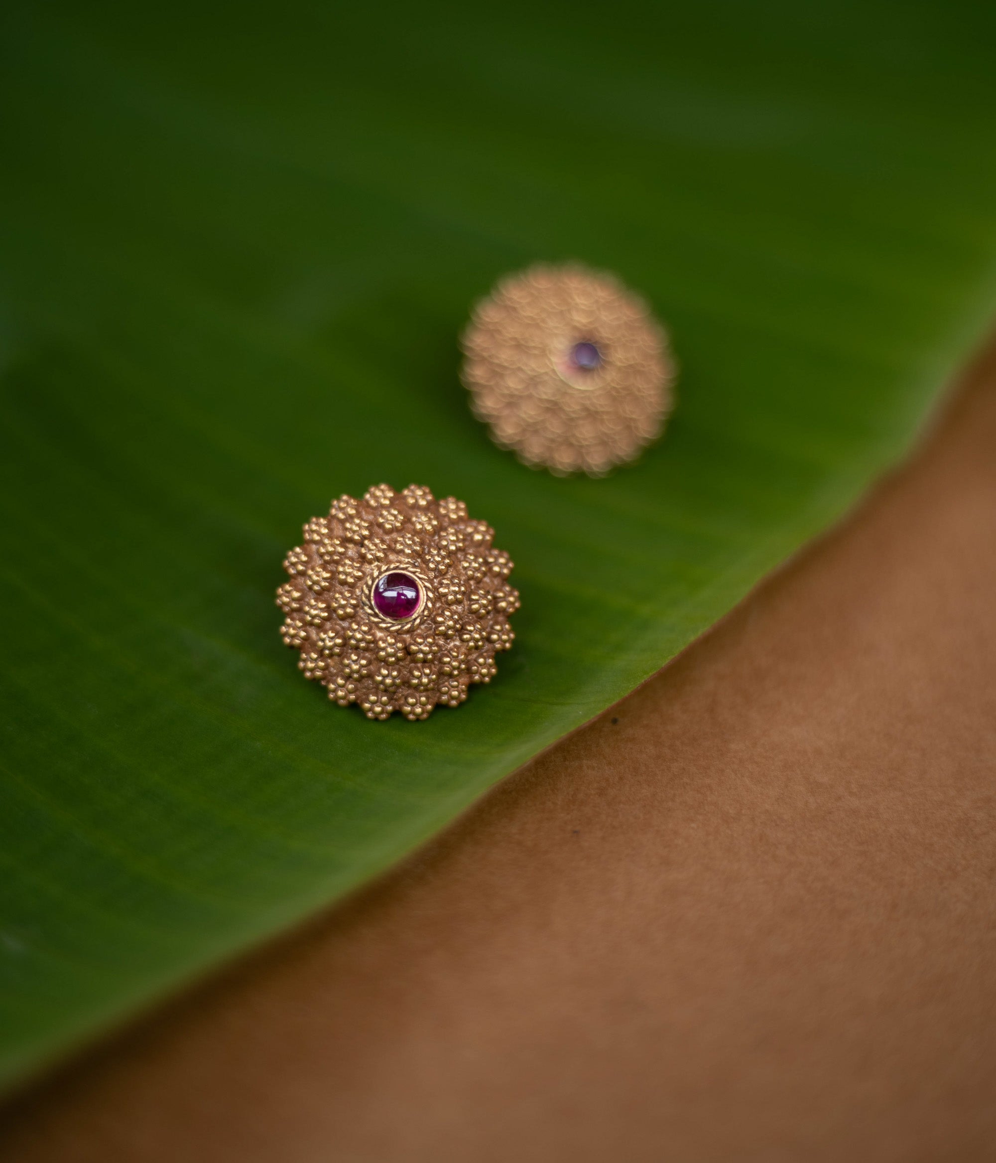 Thara earrings featuring red spinel stones in a floral crest design, made of 92.5 sterling silver with 22ct gold plating.