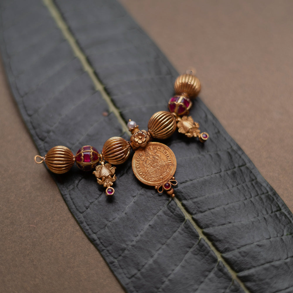 Antique Mangalsutra pendant with Lakshmi coin, red spinel stones, pearls, and floral detailing.