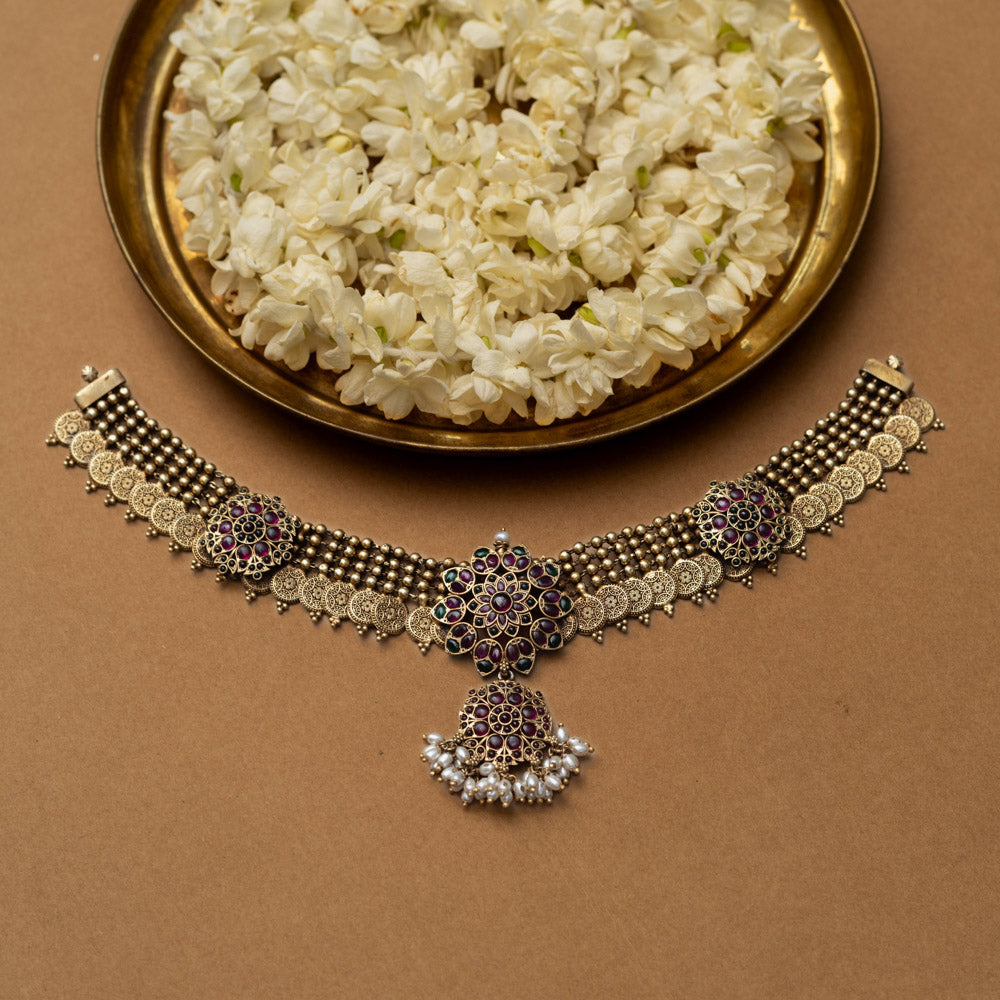 A 92.5 sterling silver Amara Antique Temple Choker, likely gold-plated, featuring lotus-inspired motifs with deep purple and ruby accents and delicate dangling pearls beneath a central pendant, embodying vintage grace for timeless elegance and sacred celebration.