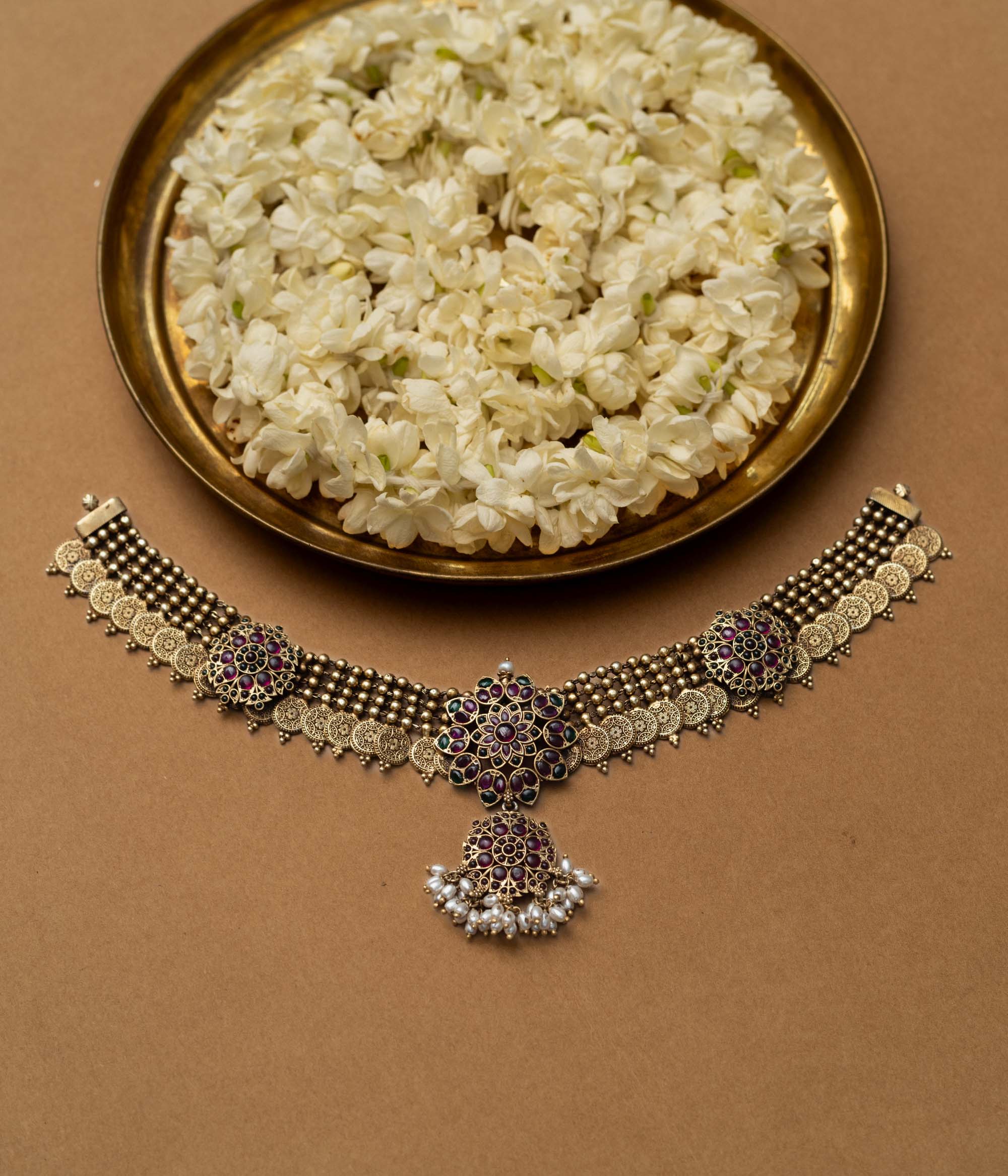 A 92.5 sterling silver Amara Antique Temple Choker, likely gold-plated, featuring lotus-inspired motifs with deep purple and ruby accents and delicate dangling pearls beneath a central pendant, embodying vintage grace for timeless elegance and sacred celebration.