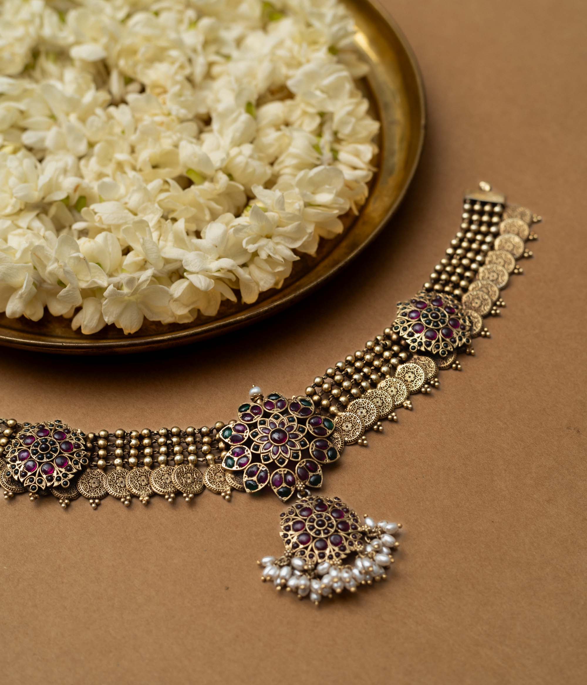 A 92.5 sterling silver Amara Antique Temple Choker, likely gold-plated, featuring lotus-inspired motifs with deep purple and ruby accents and delicate dangling pearls beneath a central pendant, embodying vintage grace for timeless elegance and sacred celebration.