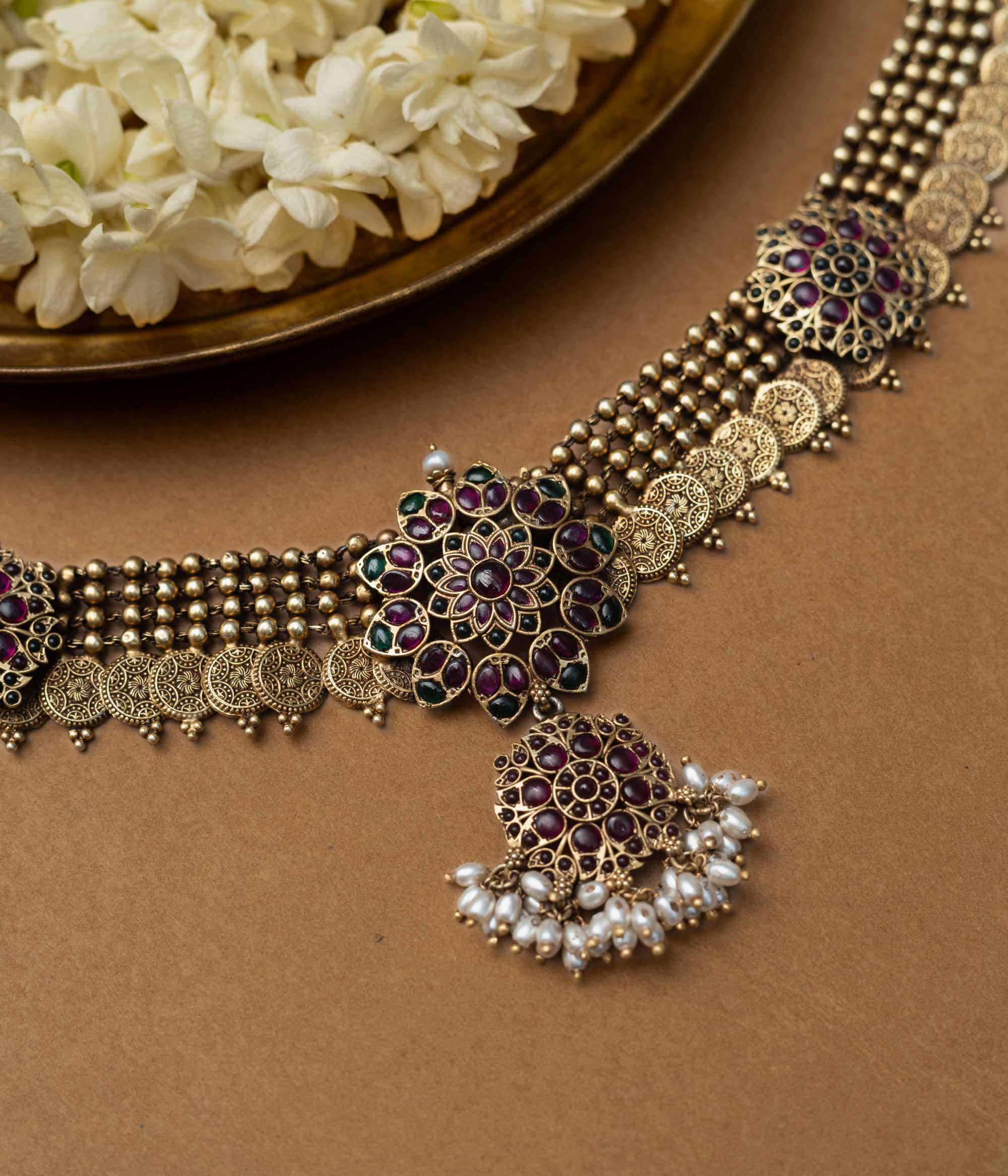 A 92.5 sterling silver Amara Antique Temple Choker, likely gold-plated, featuring lotus-inspired motifs with deep purple and ruby accents and delicate dangling pearls beneath a central pendant, embodying vintage grace for timeless elegance and sacred celebration.