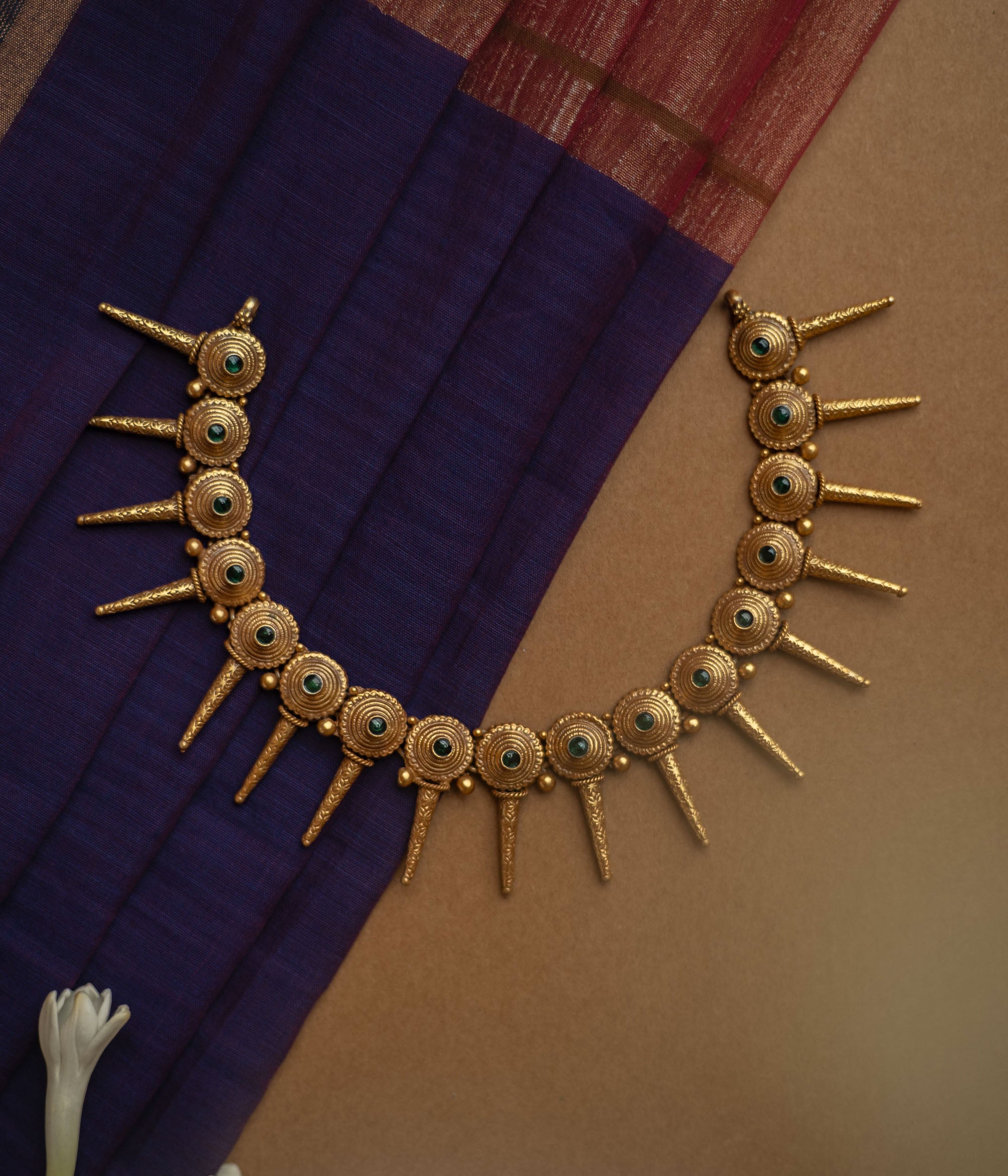 Antique gold necklace with radiating spike motifs, each set with a green spinel stone.
