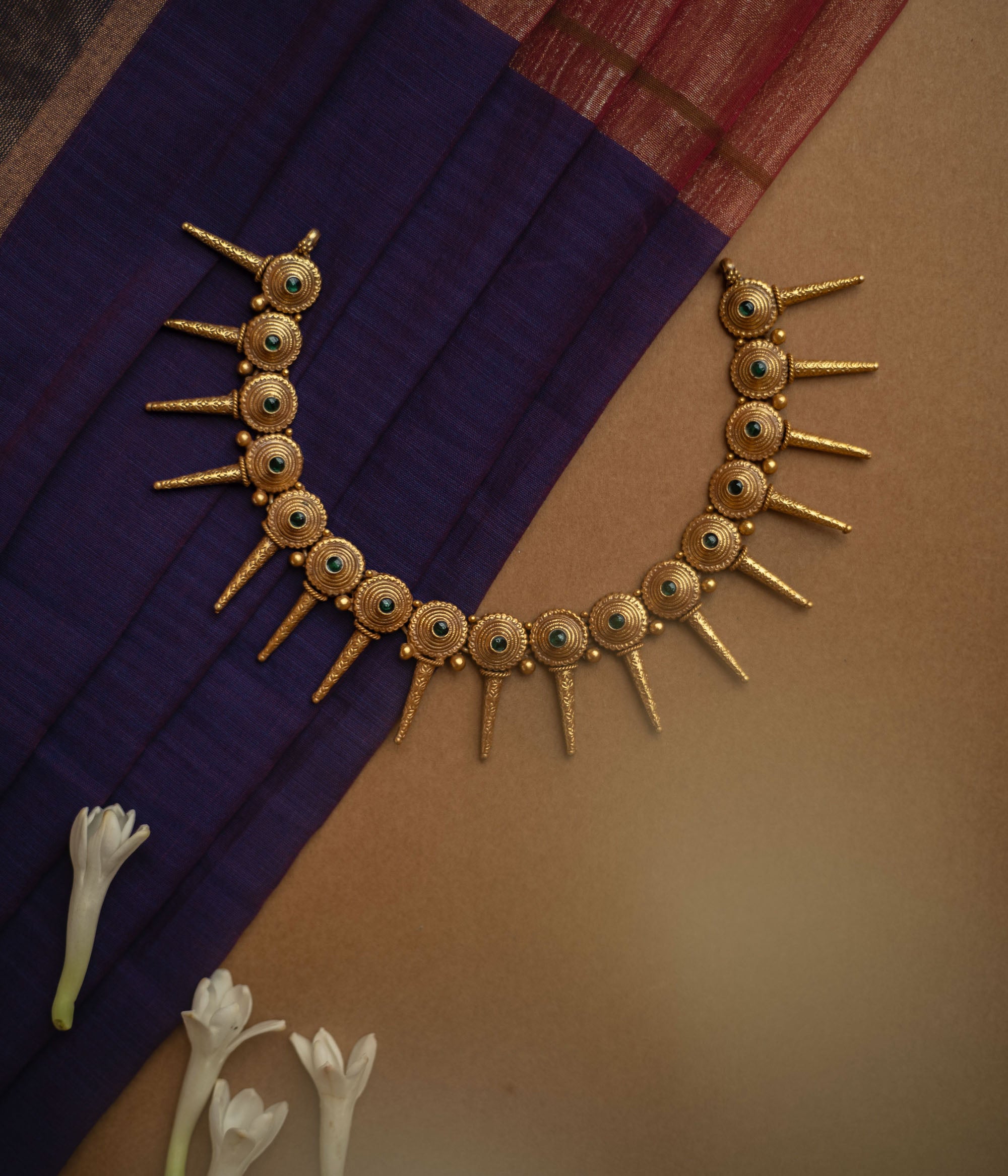 Antique gold necklace with radiating spike motifs, each set with a green spinel stone.