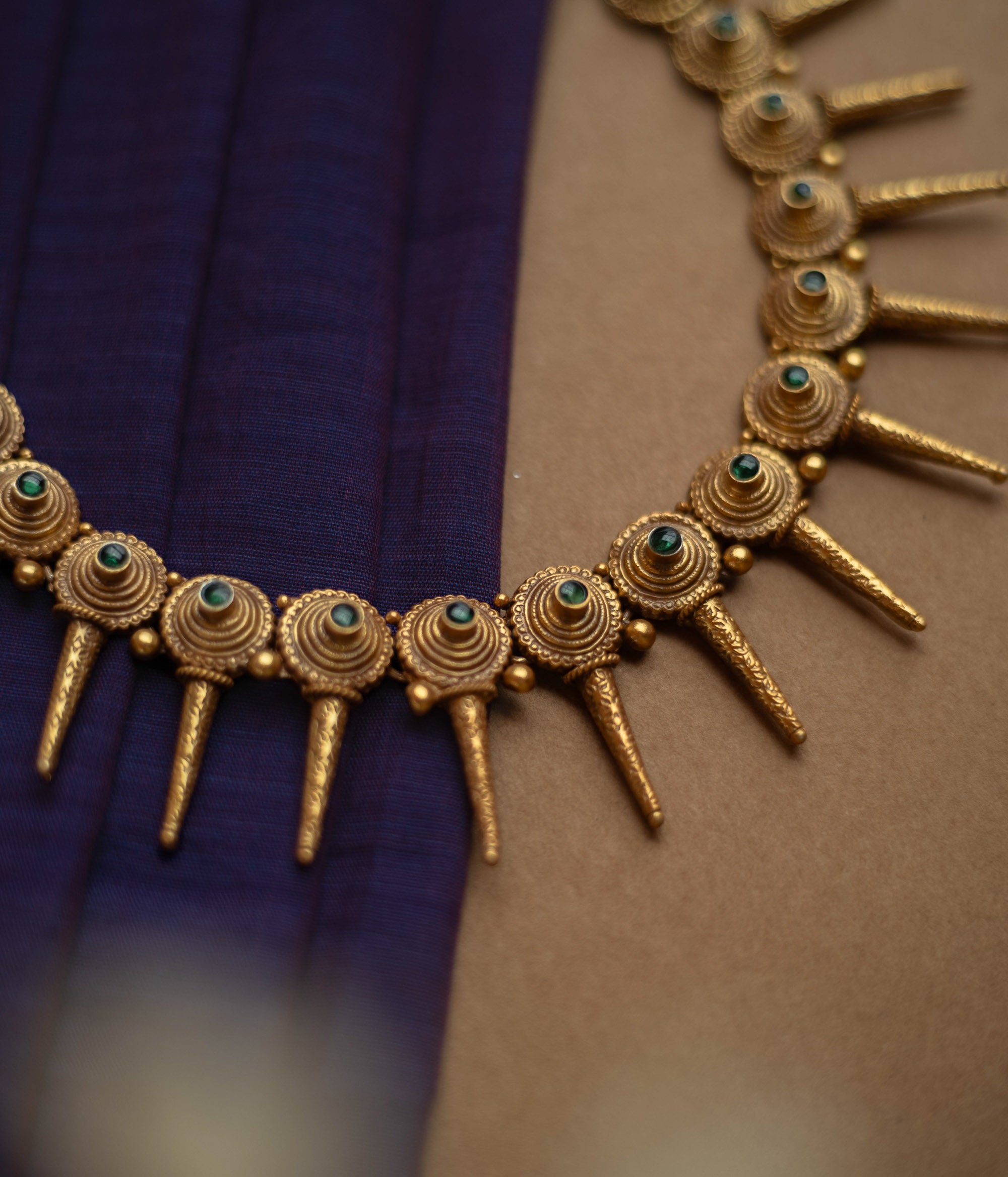 Antique gold necklace with radiating spike motifs, each set with a green spinel stone.