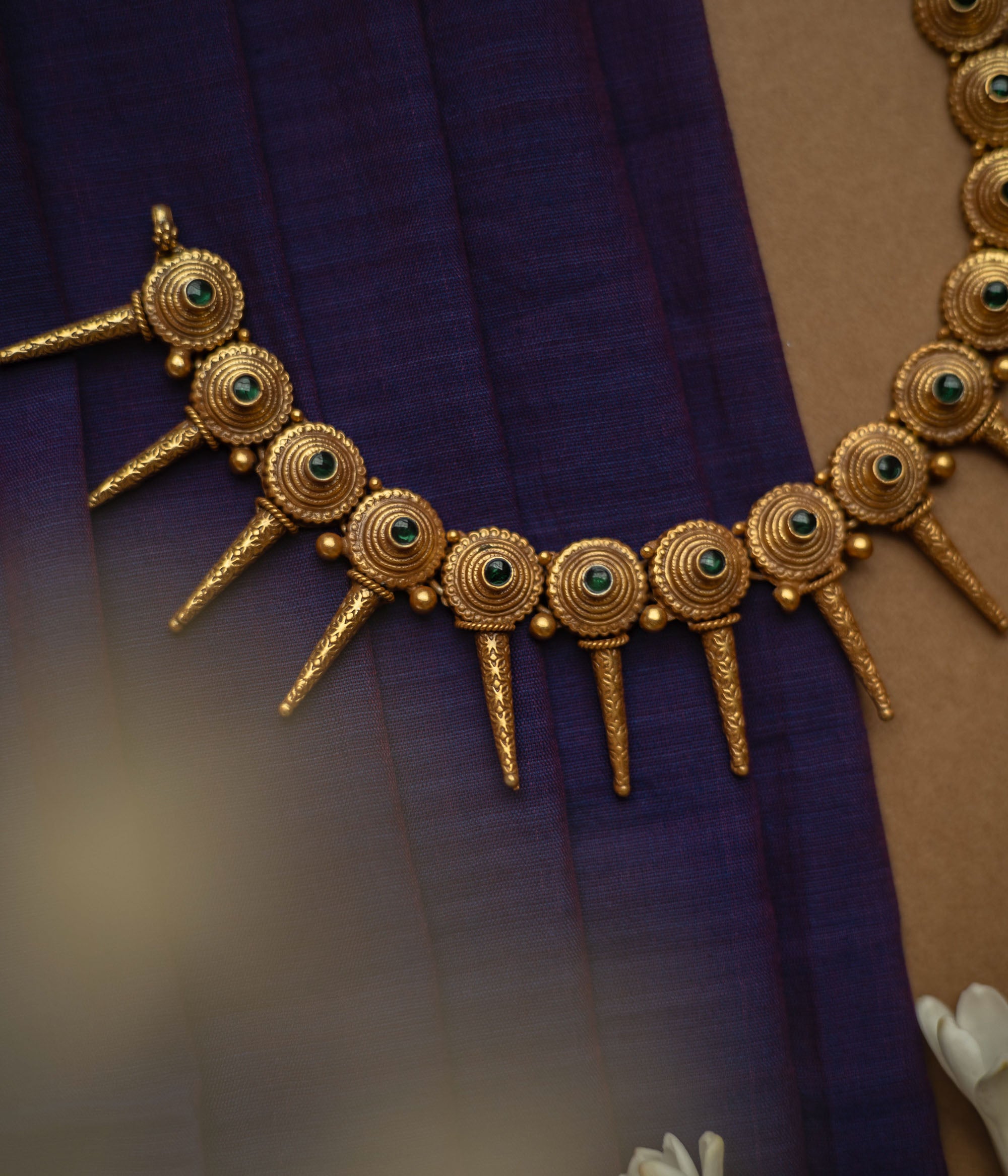Antique gold necklace with radiating spike motifs, each set with a green spinel stone.