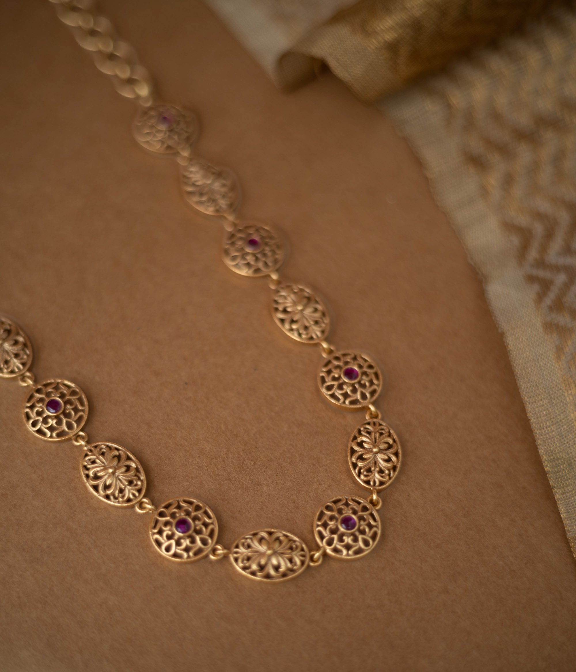 Antique gold necklace with red spinel stones in traditional circular and oval motifs.