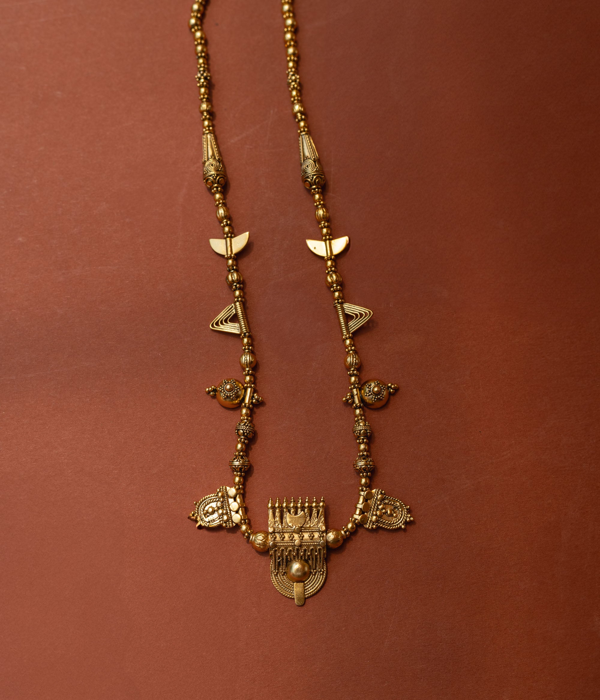 Traditional tribal gold necklace with temple motifs, half-moon shapes, and horn accents from Tribal Collection.