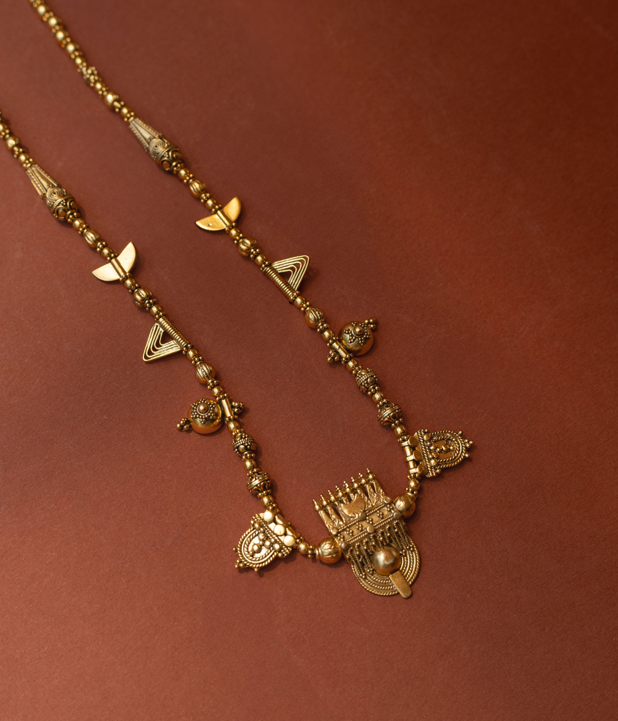 Traditional tribal gold necklace with temple motifs, half-moon shapes, and horn accents from Tribal Collection.