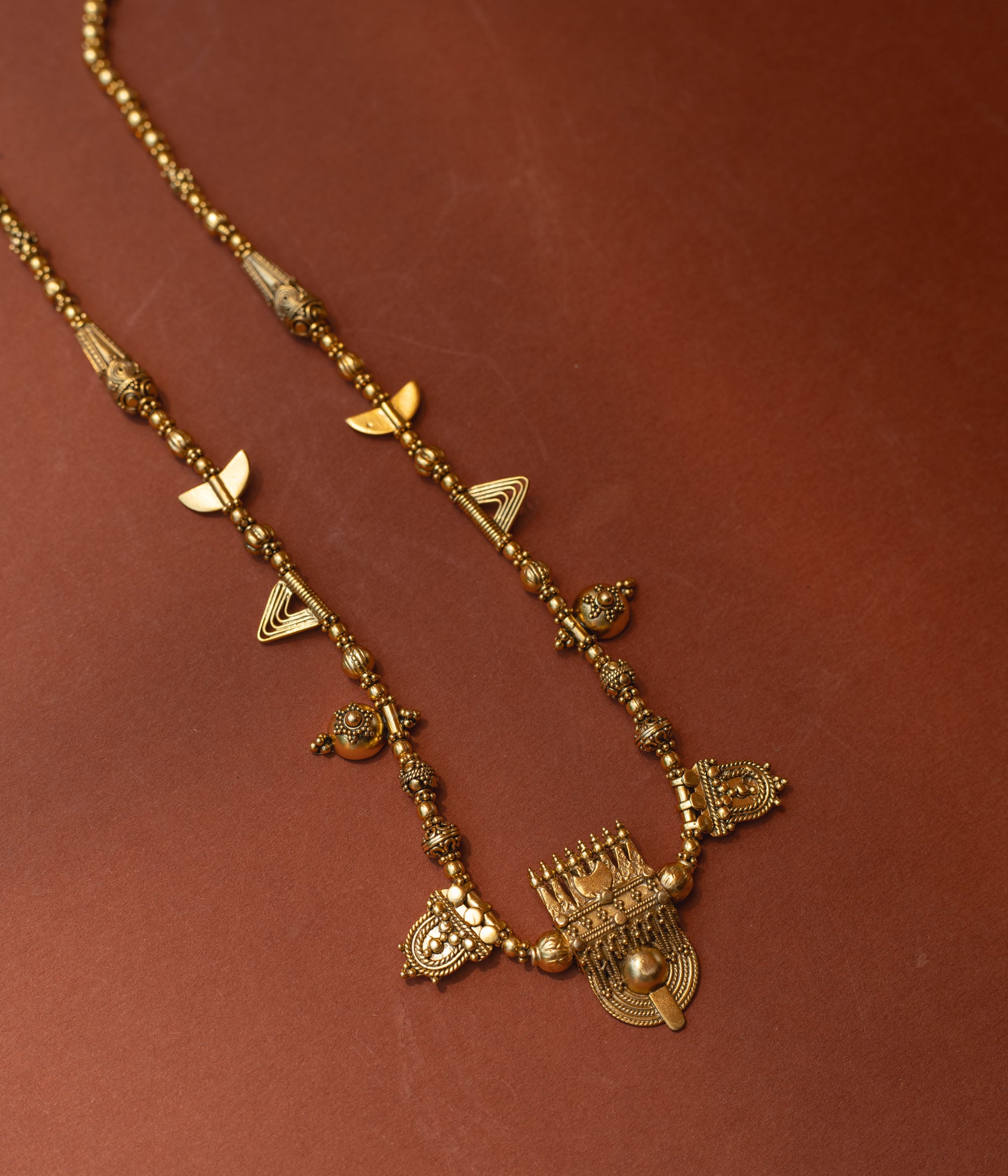 Traditional tribal gold necklace with temple motifs, half-moon shapes, and horn accents from Tribal Collection.