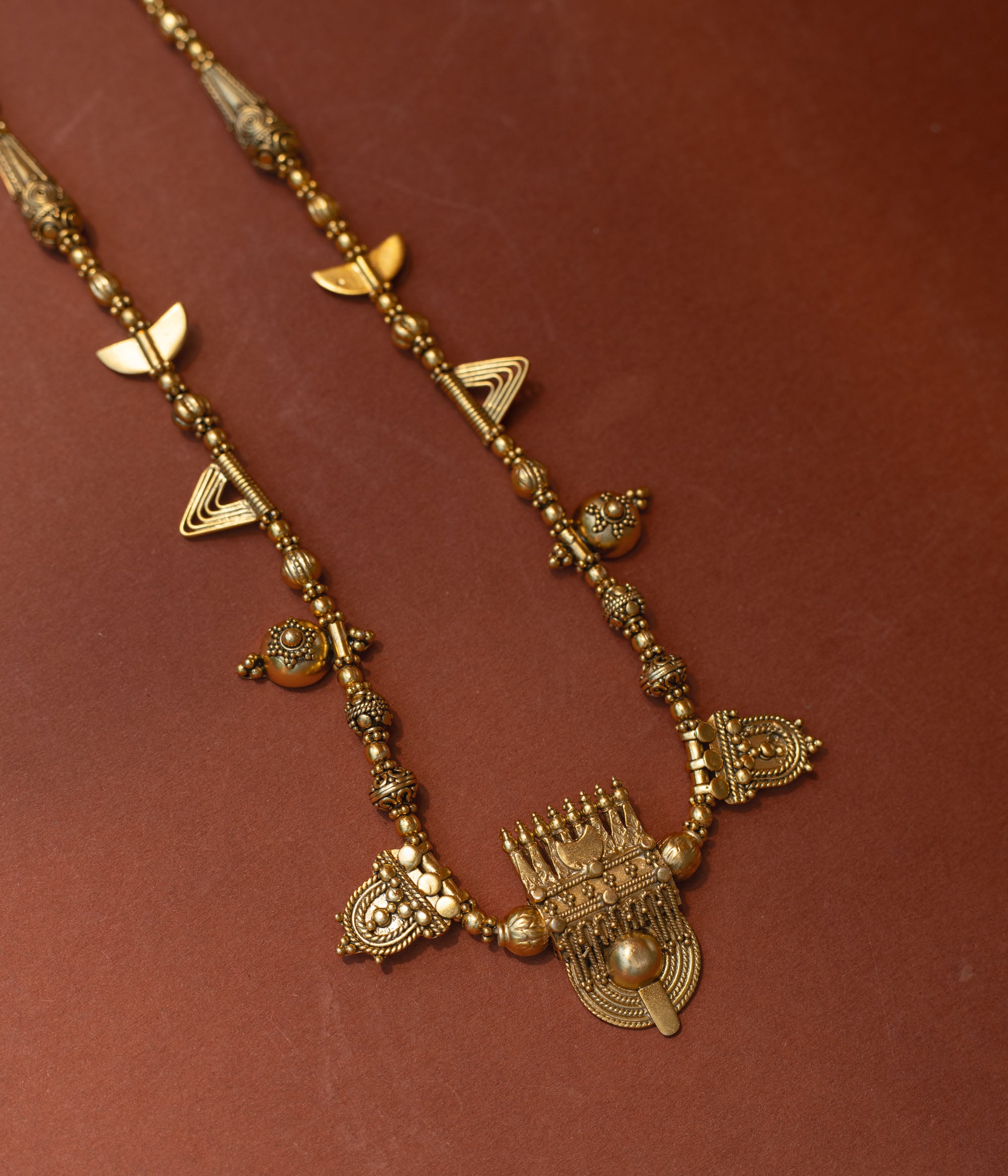 Traditional tribal gold necklace with temple motifs, half-moon shapes, and horn accents from Tribal Collection.