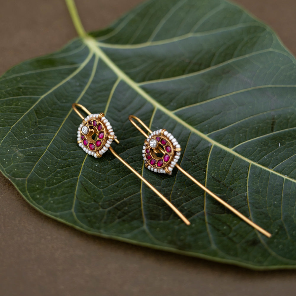 A handcrafted 92.5 sterling silver and 22ct gold-plated bugadi, featuring white and red Kundan stones and pearls, showcasing intricate gold detailing and embodying heritage and grace.