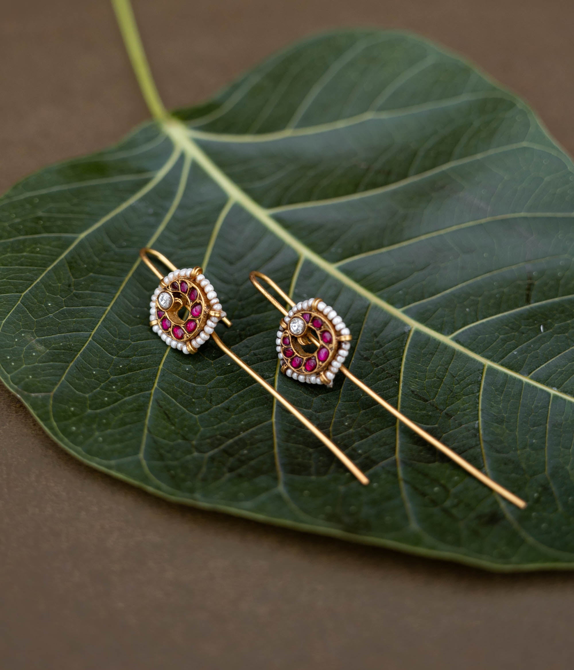 A handcrafted 92.5 sterling silver and 22ct gold-plated bugadi, featuring white and red Kundan stones and pearls, showcasing intricate gold detailing and embodying heritage and grace.