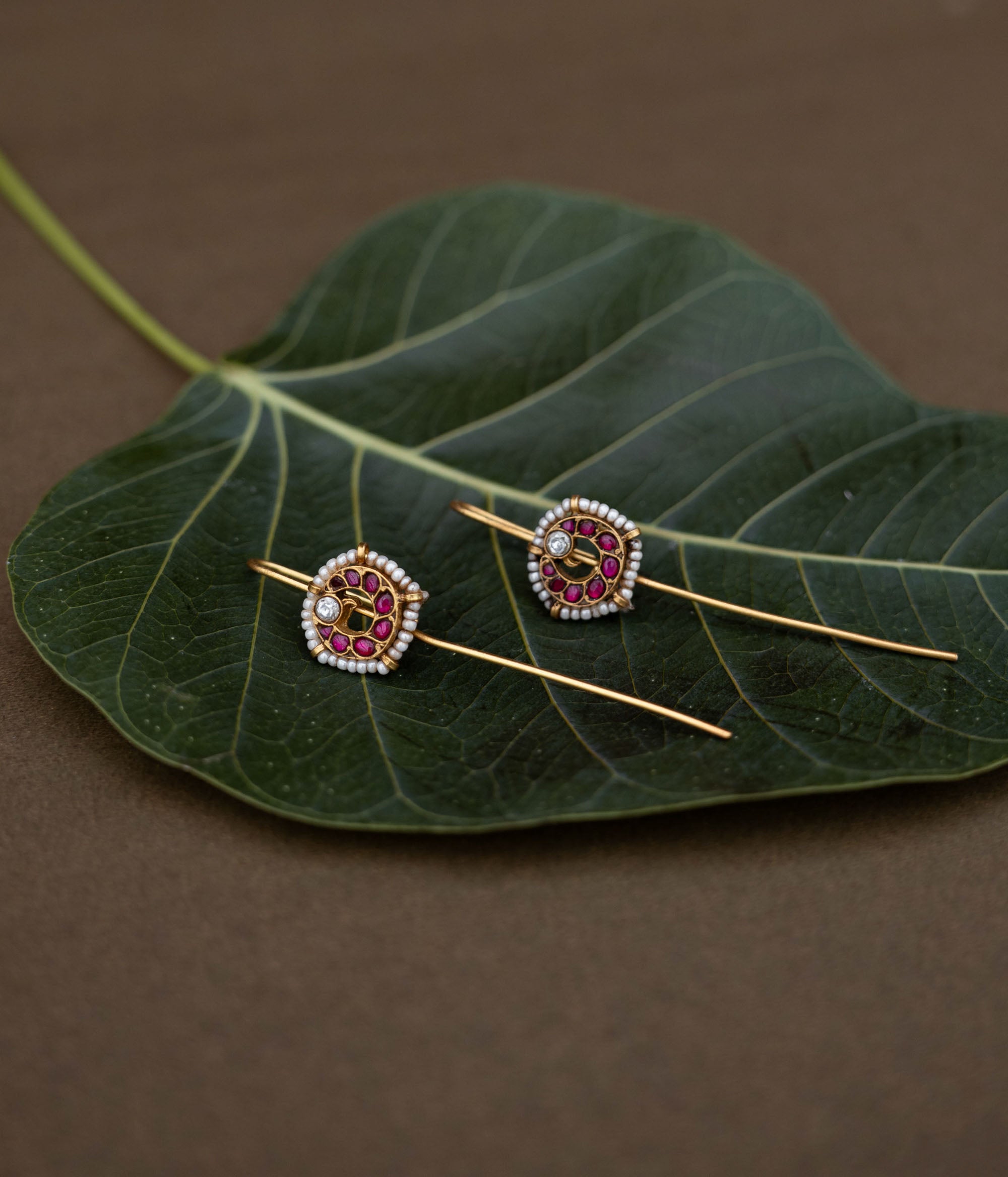A handcrafted 92.5 sterling silver and 22ct gold-plated bugadi, featuring white and red Kundan stones and pearls, showcasing intricate gold detailing and embodying heritage and grace.