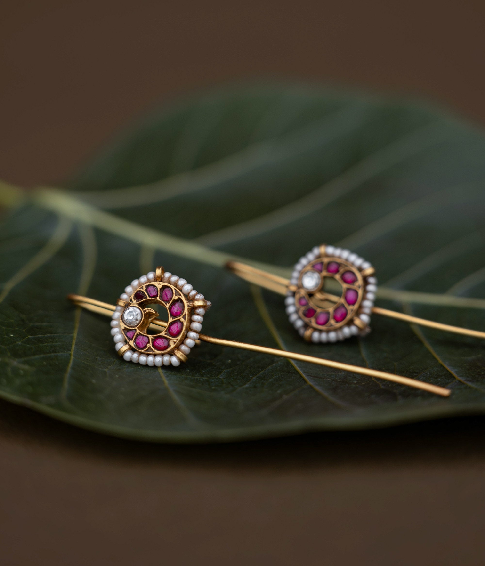A handcrafted 92.5 sterling silver and 22ct gold-plated bugadi, featuring white and red Kundan stones and pearls, showcasing intricate gold detailing and embodying heritage and grace.
