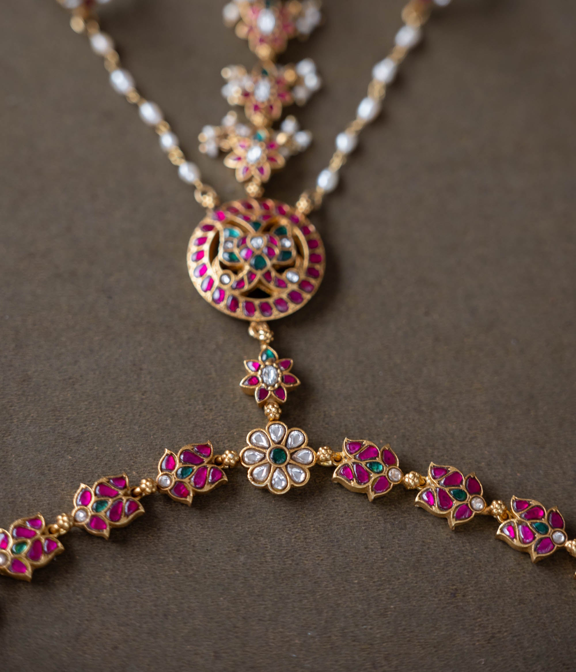 Handmade 92.5 sterling silver and 22ct gold-plated Trishika Haathphool, adorned with white, red, and green Kundan stones and pearls. An intricate masterpiece of elegance and tradition, weaving royal charm with delicate floral accents.