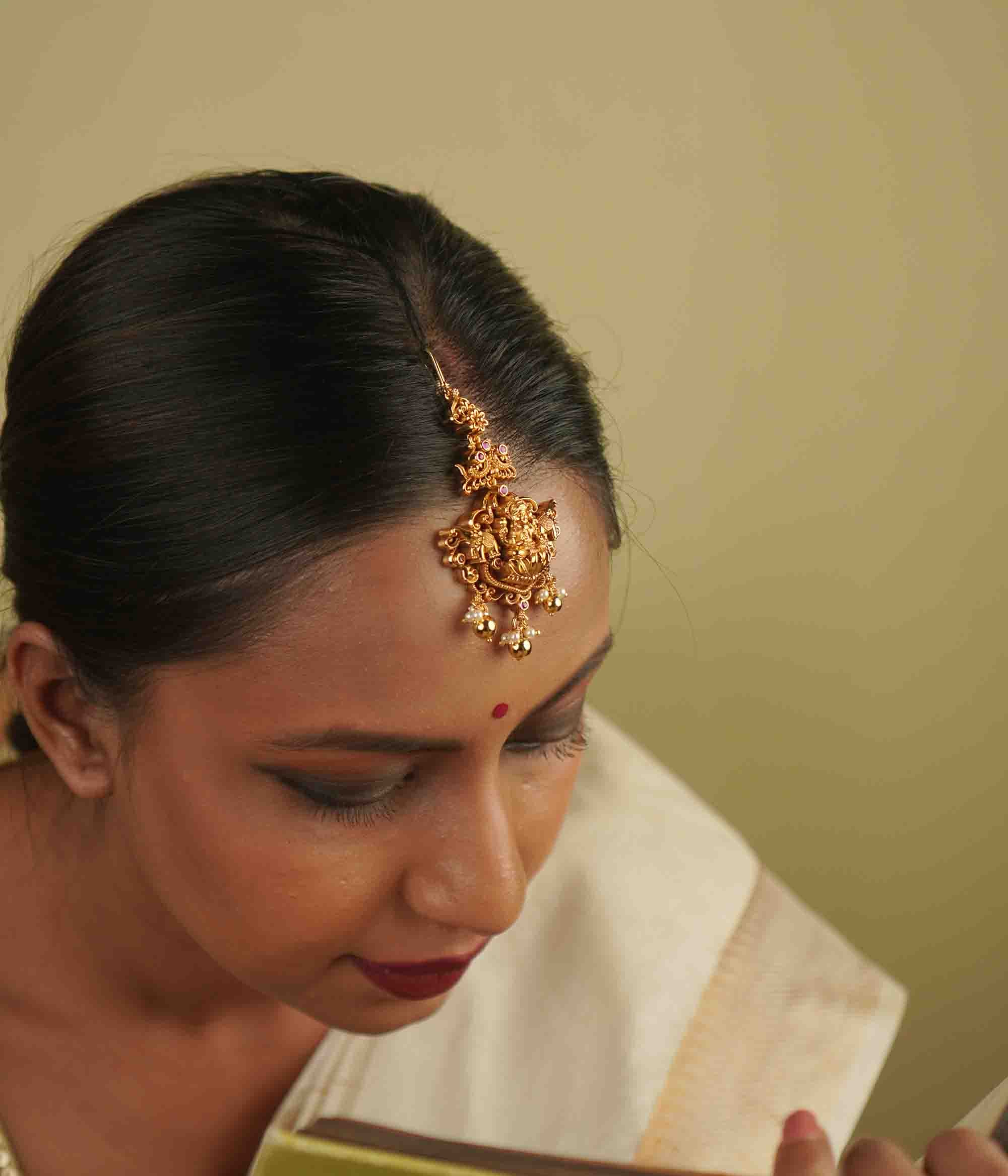 Ura Maangtika: A celebration of vintage charm, reborn. Gold-plated silver adorned with goddess motifs and delicate pearl droplets, blending timeless temple artistry with whimsical elegance, perfect for the modern bride.