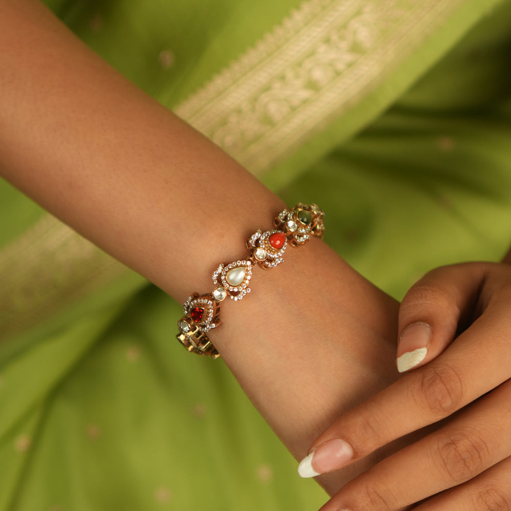 Celestial whispers reborn! This gold-plated bracelet, adorned with vibrant Navaratna stones encircled by shimmering CZ, weaves ancient wisdom with modern elegance—a cosmic symphony for the modern woman.