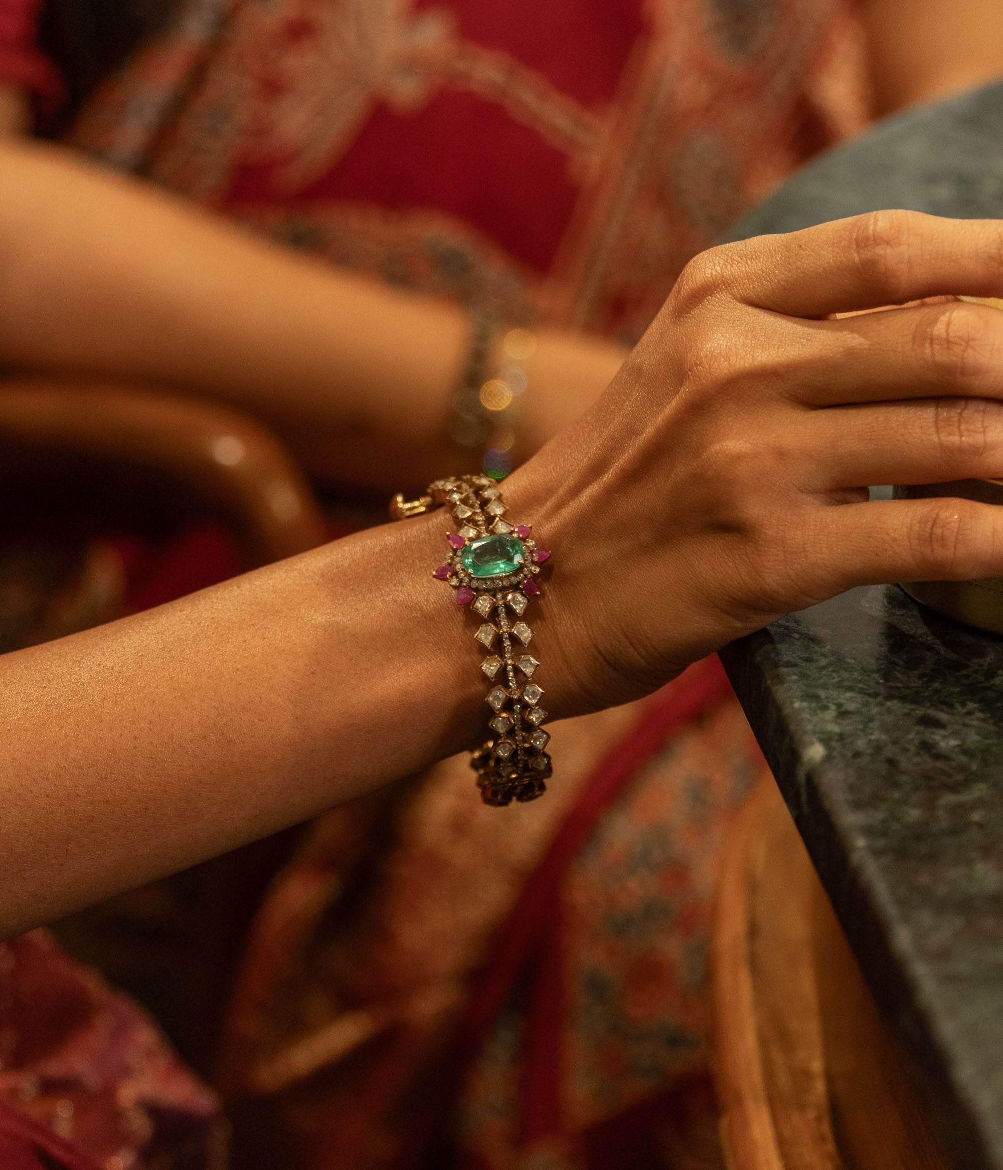 Gold Victorian bangle with a central green gemstone, surrounding polki and CZ stones, worn on a woman's wrist.