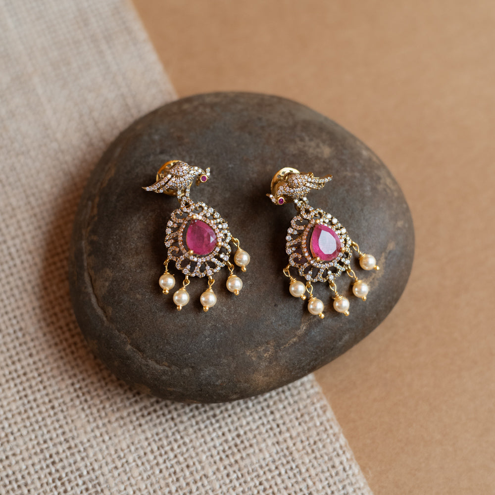 Gold Victorian drop earrings with a bird motif, pink teardrop gemstones, CZ stones, and dangling pearls.