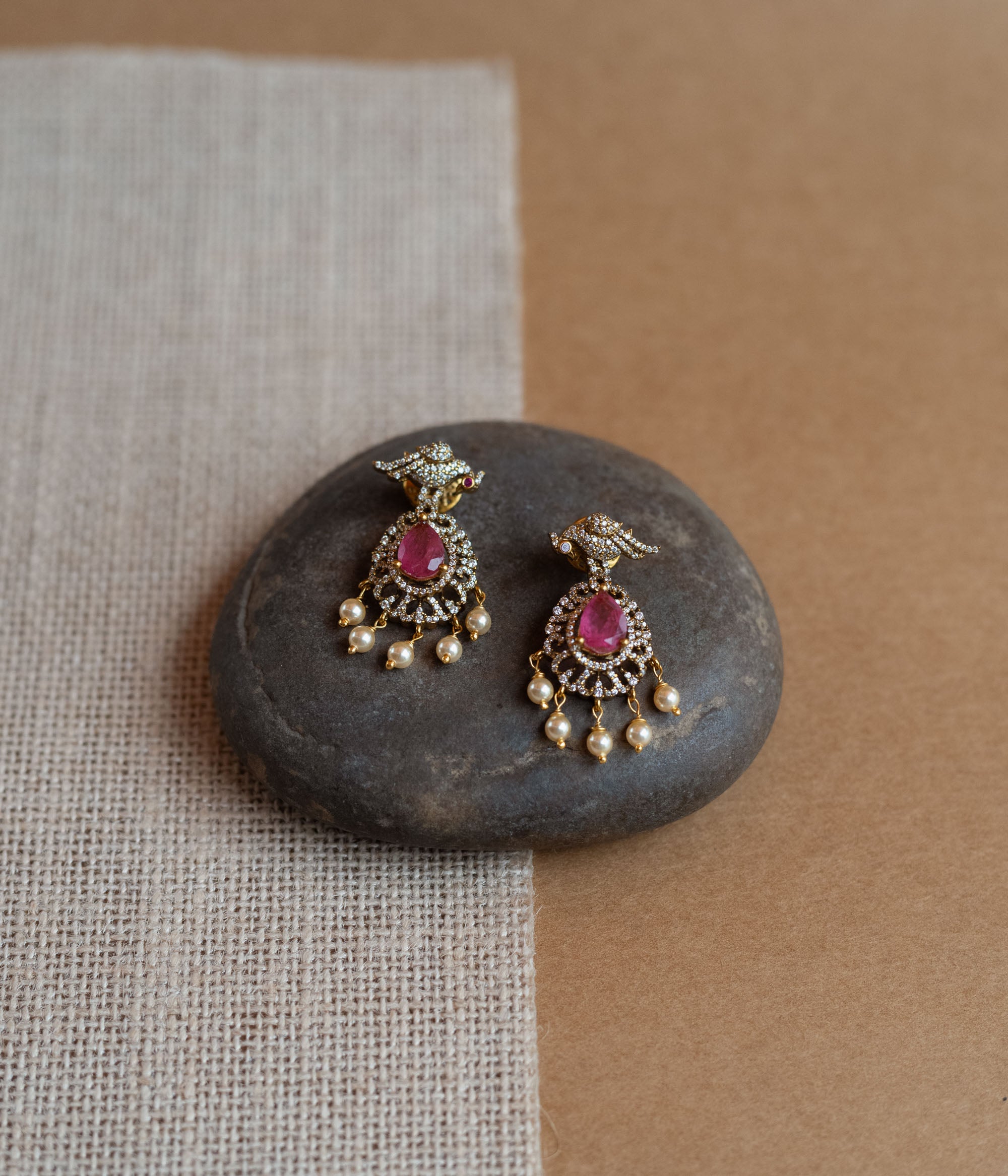 Gold Victorian drop earrings with a bird motif, pink teardrop gemstones, CZ stones, and dangling pearls.