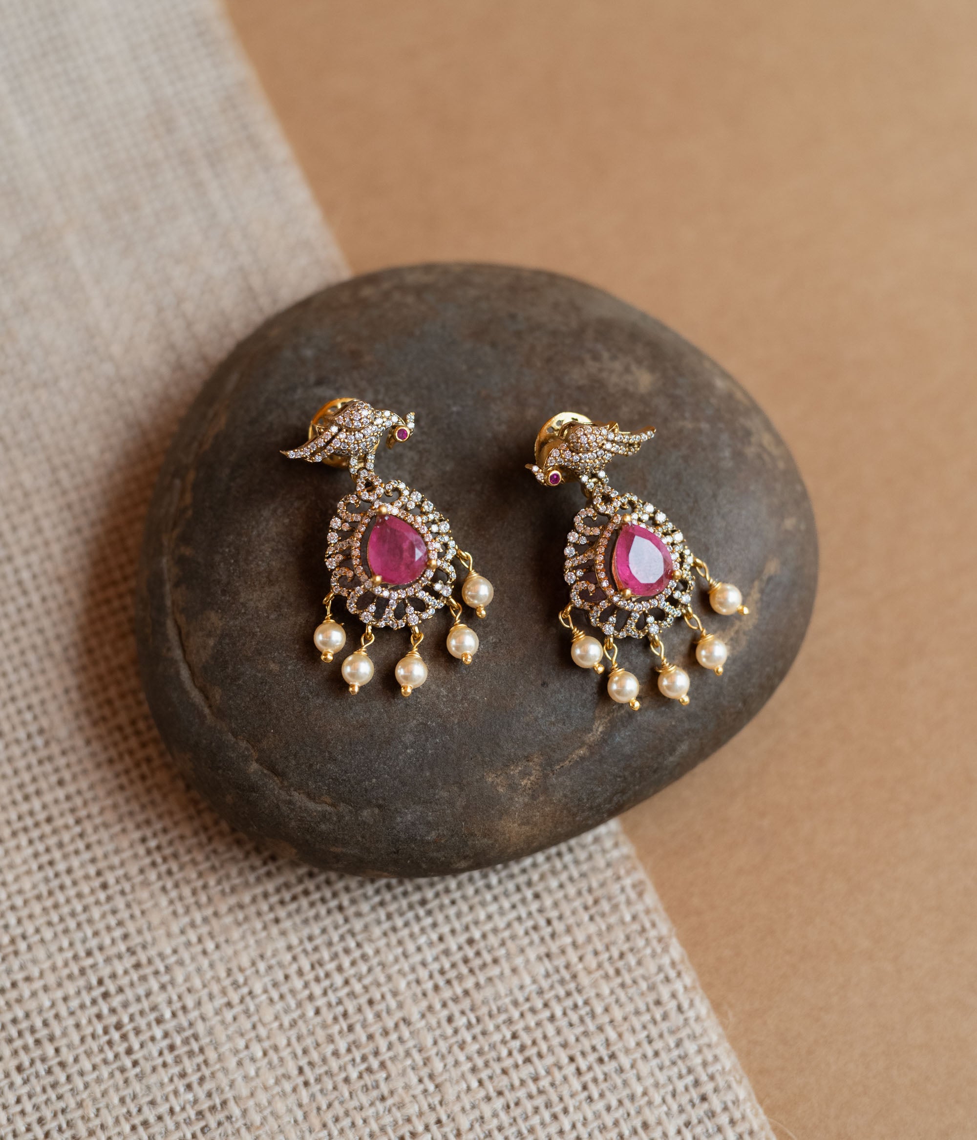 Gold Victorian drop earrings with a bird motif, pink teardrop gemstones, CZ stones, and dangling pearls.