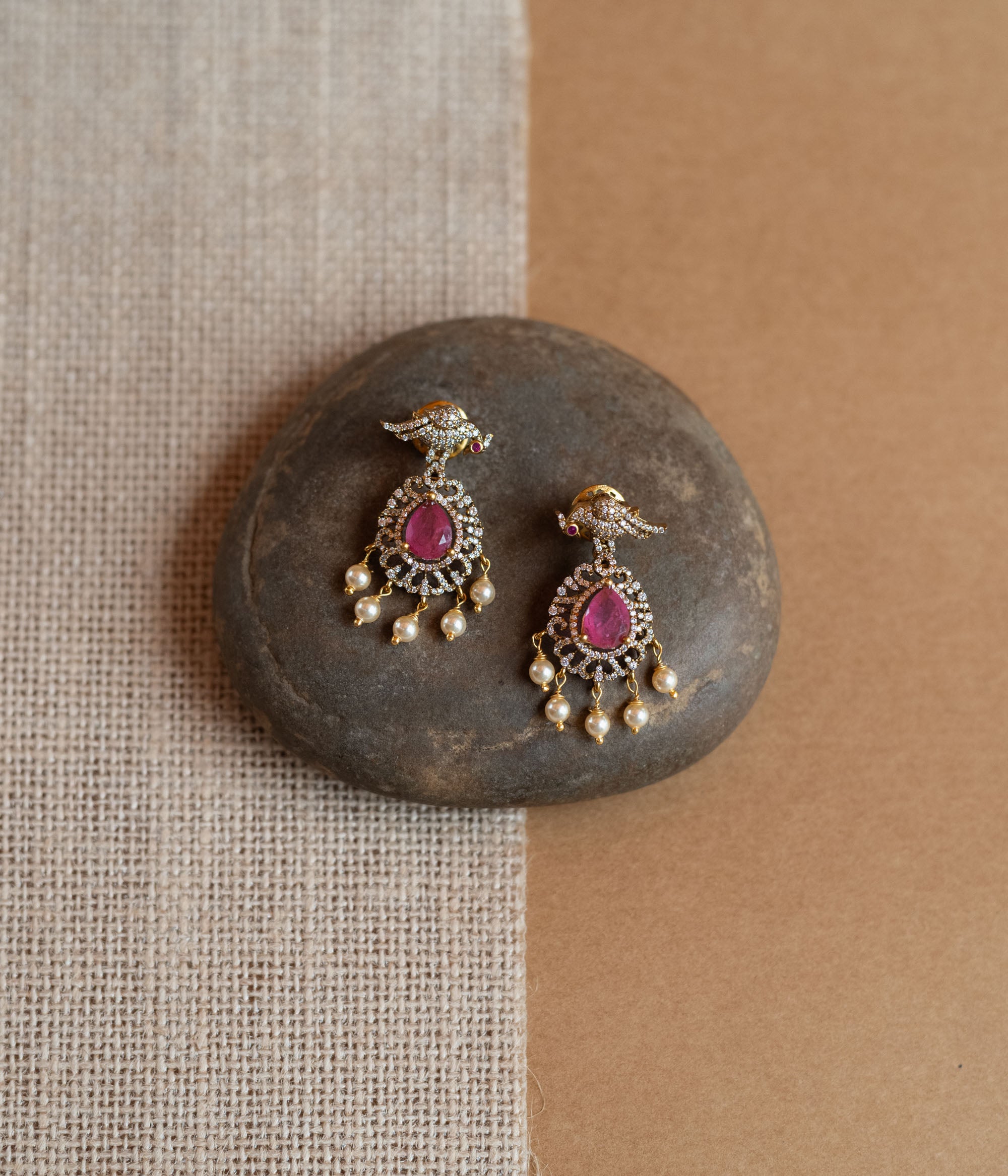 Gold Victorian drop earrings with a bird motif, pink teardrop gemstones, CZ stones, and dangling pearls.