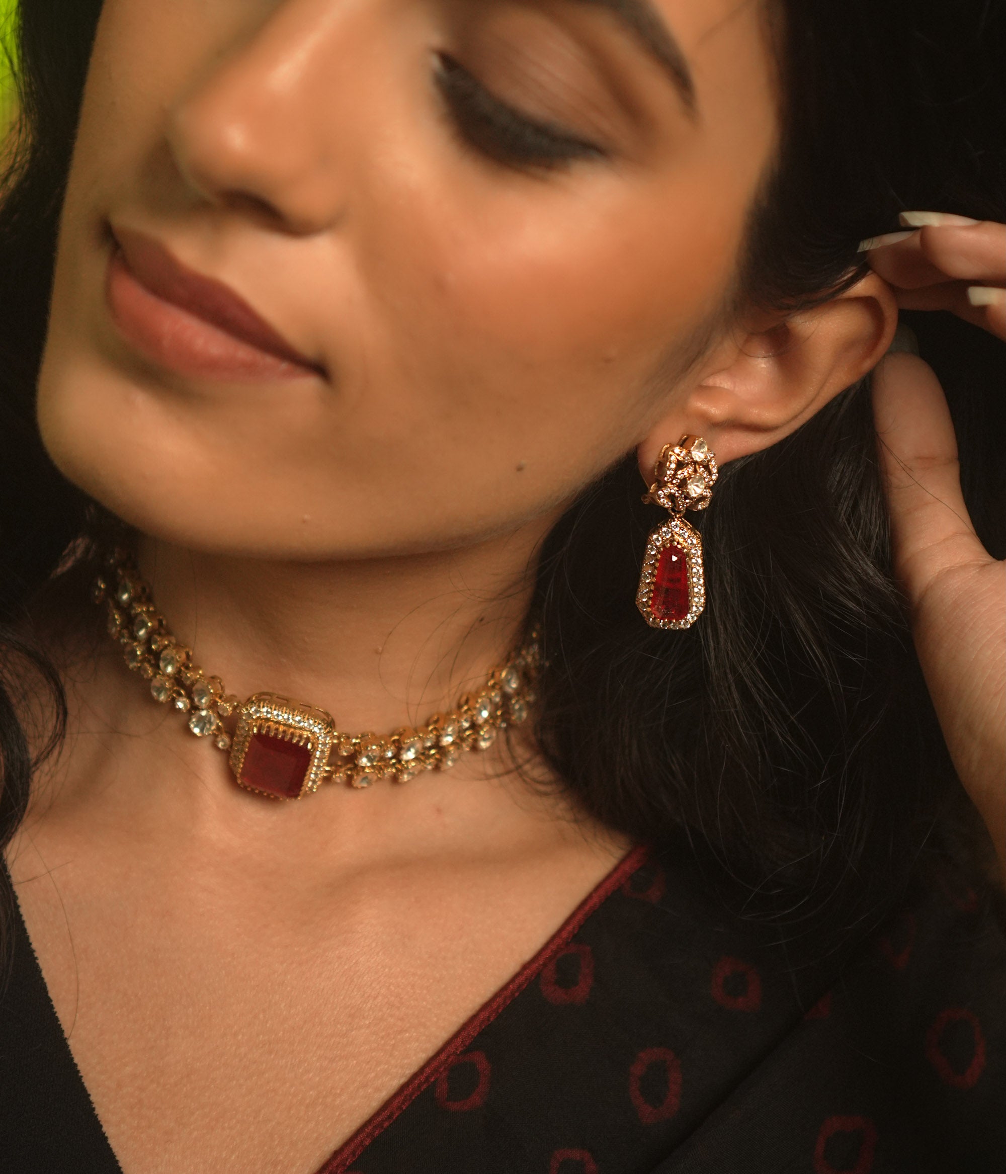 Gold earrings with a floral top, a large red stone, and a drop of white moissanite.
