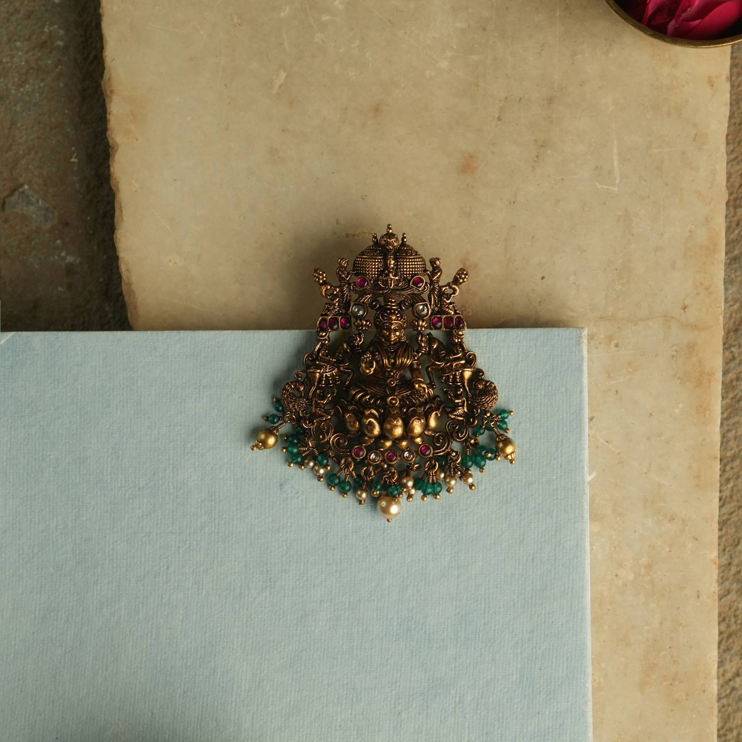 Adorn yourself with serenity and timeless elegance with our exquisite Nakshi pendant, featuring a divine Goddess Lakshmi motif, intricately crafted with red and white Kundan stones. A true symbol of grace and heritage.