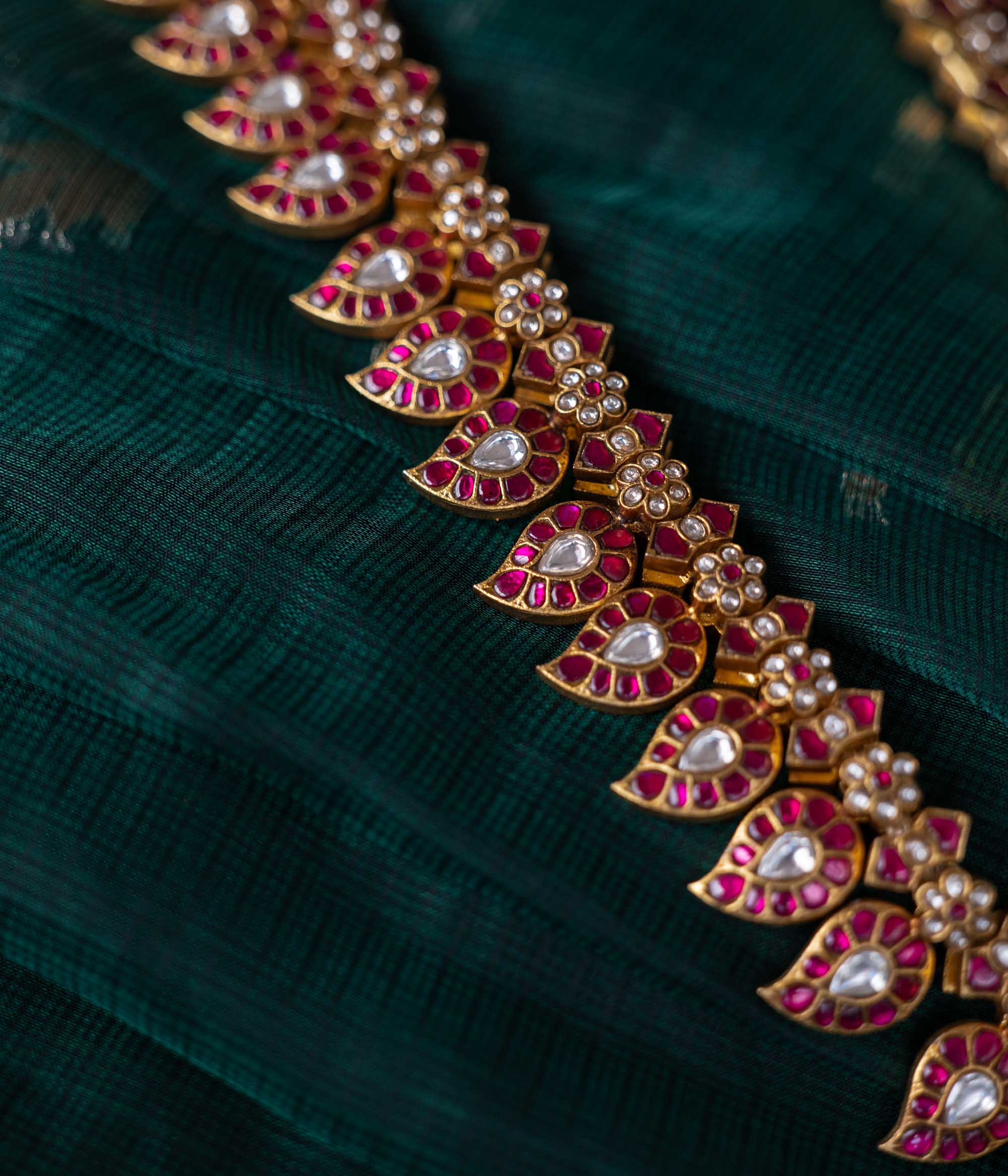 A handcrafted two-sided Kundan necklace in 92.5 sterling silver with 22ct gold plating, adorned with red, white, and green Kundan stones, red beads, and pearls. This versatile masterpiece exudes timeless elegance, blending heritage craftsmanship with regal charm.