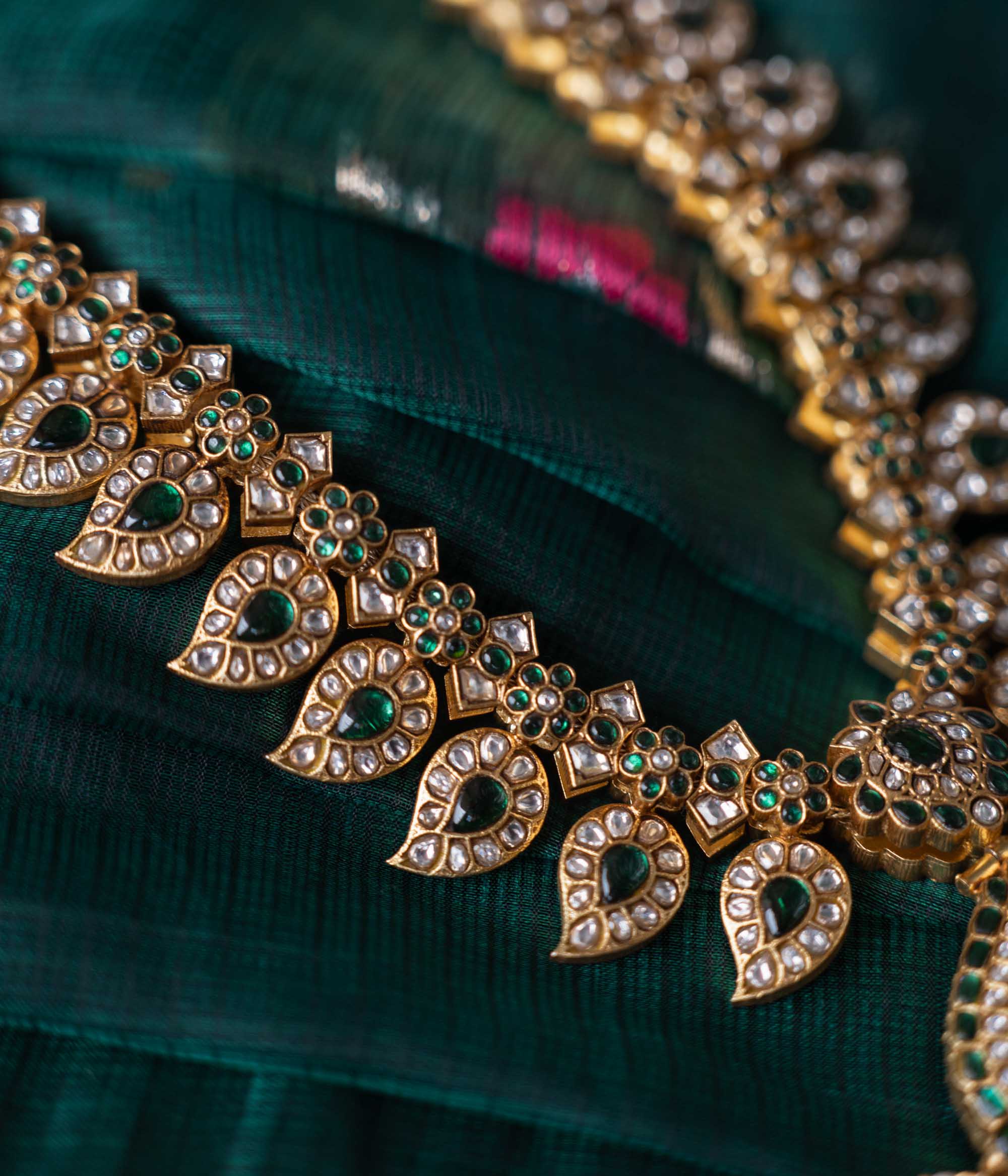 A handcrafted two-sided Kundan necklace in 92.5 sterling silver with 22ct gold plating, adorned with red, white, and green Kundan stones, red beads, and pearls. This versatile masterpiece exudes timeless elegance, blending heritage craftsmanship with regal charm.