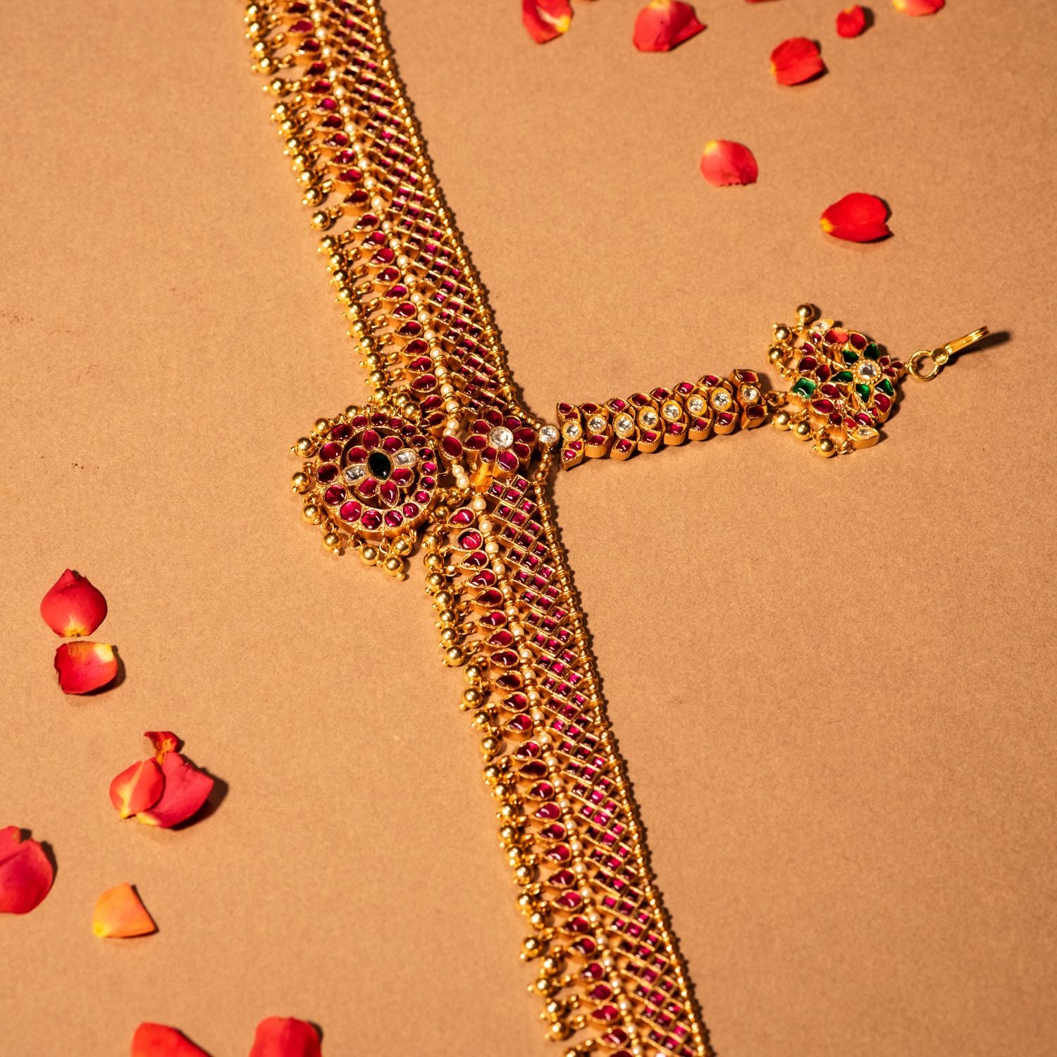 Gold-plated silver tikka with a delicate floral design, adorned with red, green, and white Kundan stones, and finished with golden drop beads, creating a traditional and graceful accessory for Bridal and Festive wear.
