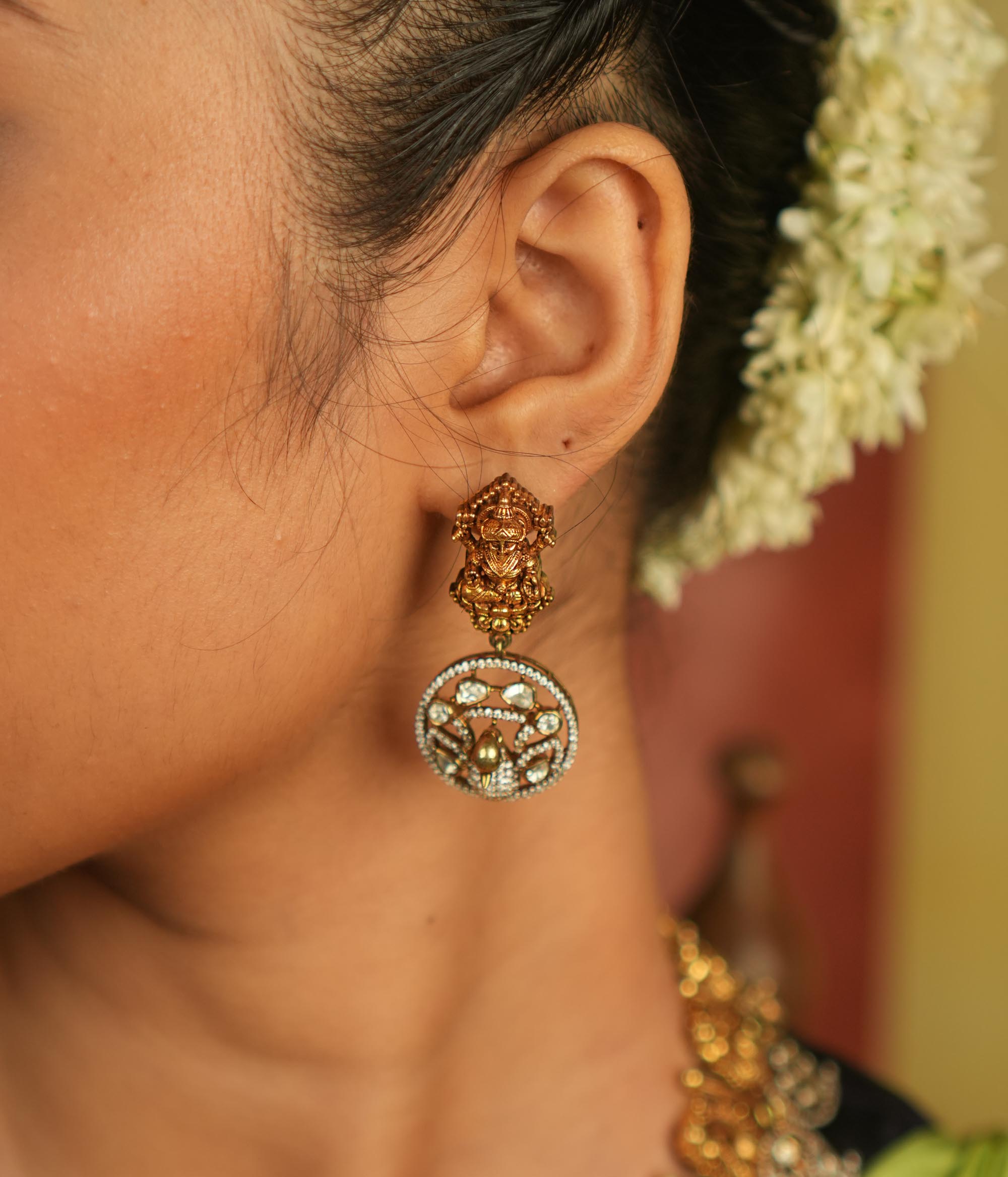 Divine elegance reborn! These gold-plated temple drop earrings feature a serene goddess Lakshmi motif on the stud, with a floral CZ stone frame below. A celestial tribute to timeless artistry and cultural grace.