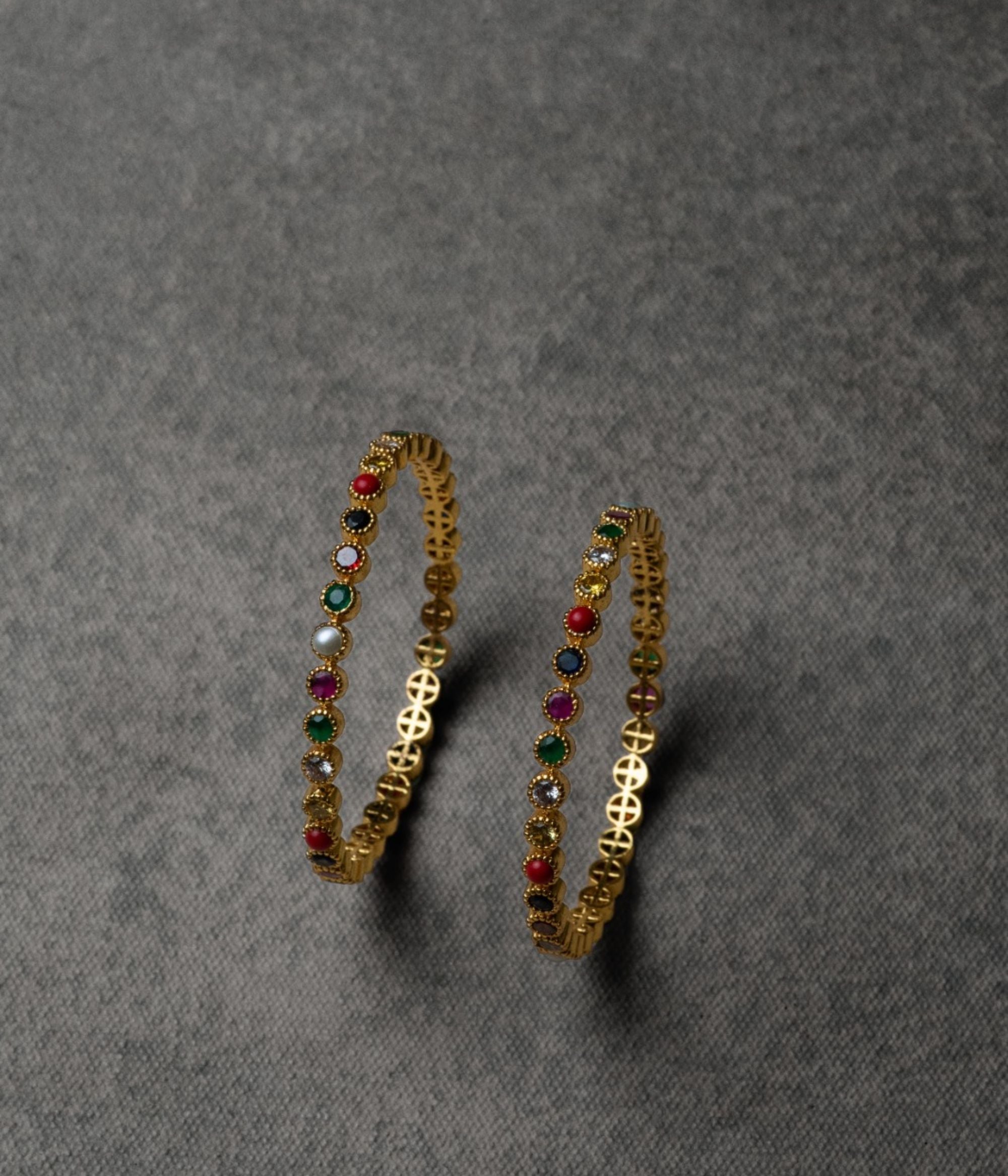 A Navratna bangle featuring nine vibrant gemstones, each symbolizing a celestial body, designed to bring good fortune and positive energy. Its exquisite charm adds both beauty and spiritual significance to any look.