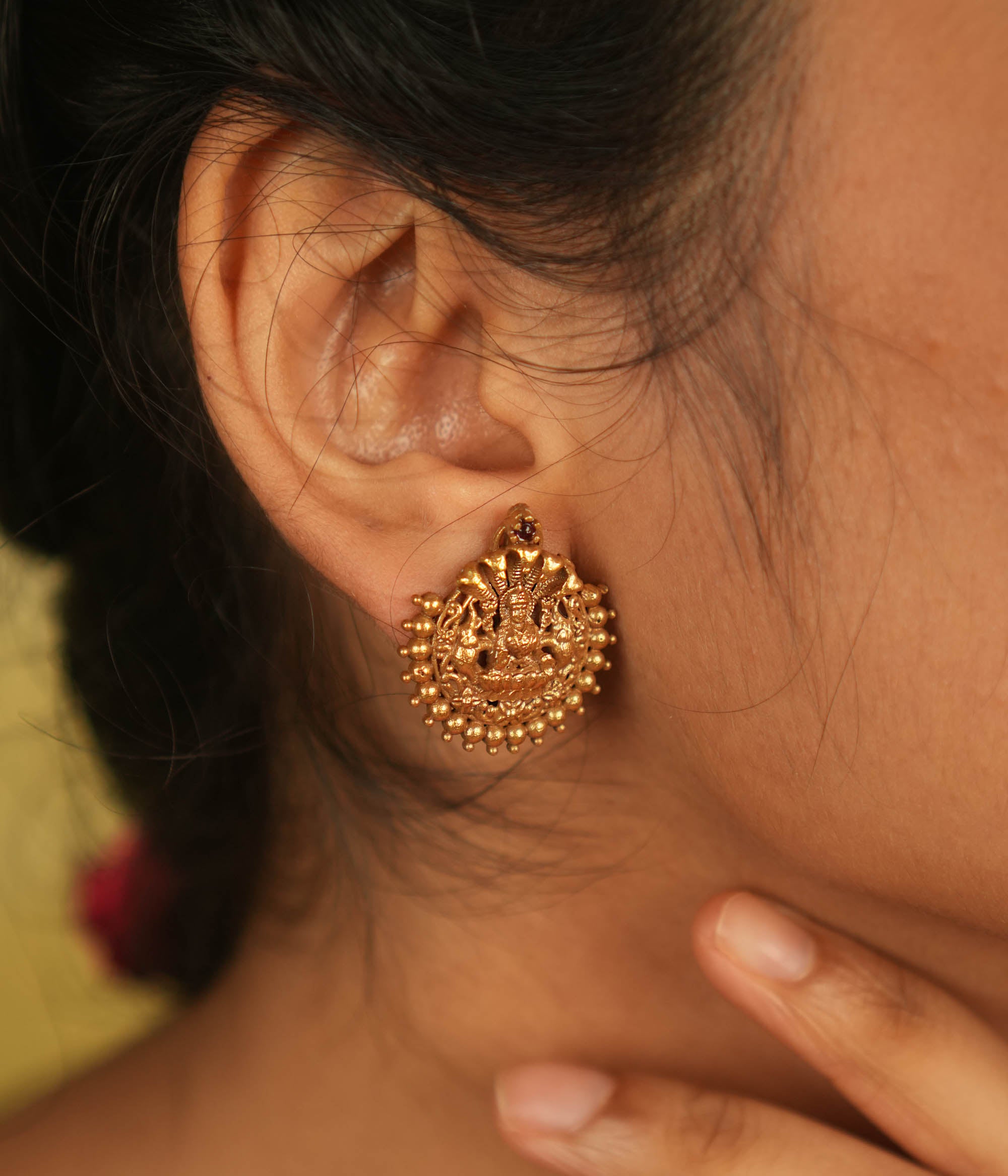 Divine elegance redefined! These gold-plated stud earrings feature Goddess Lakshmi, adorned with delicate golden beads. A perfect blend of tradition and modern charm.