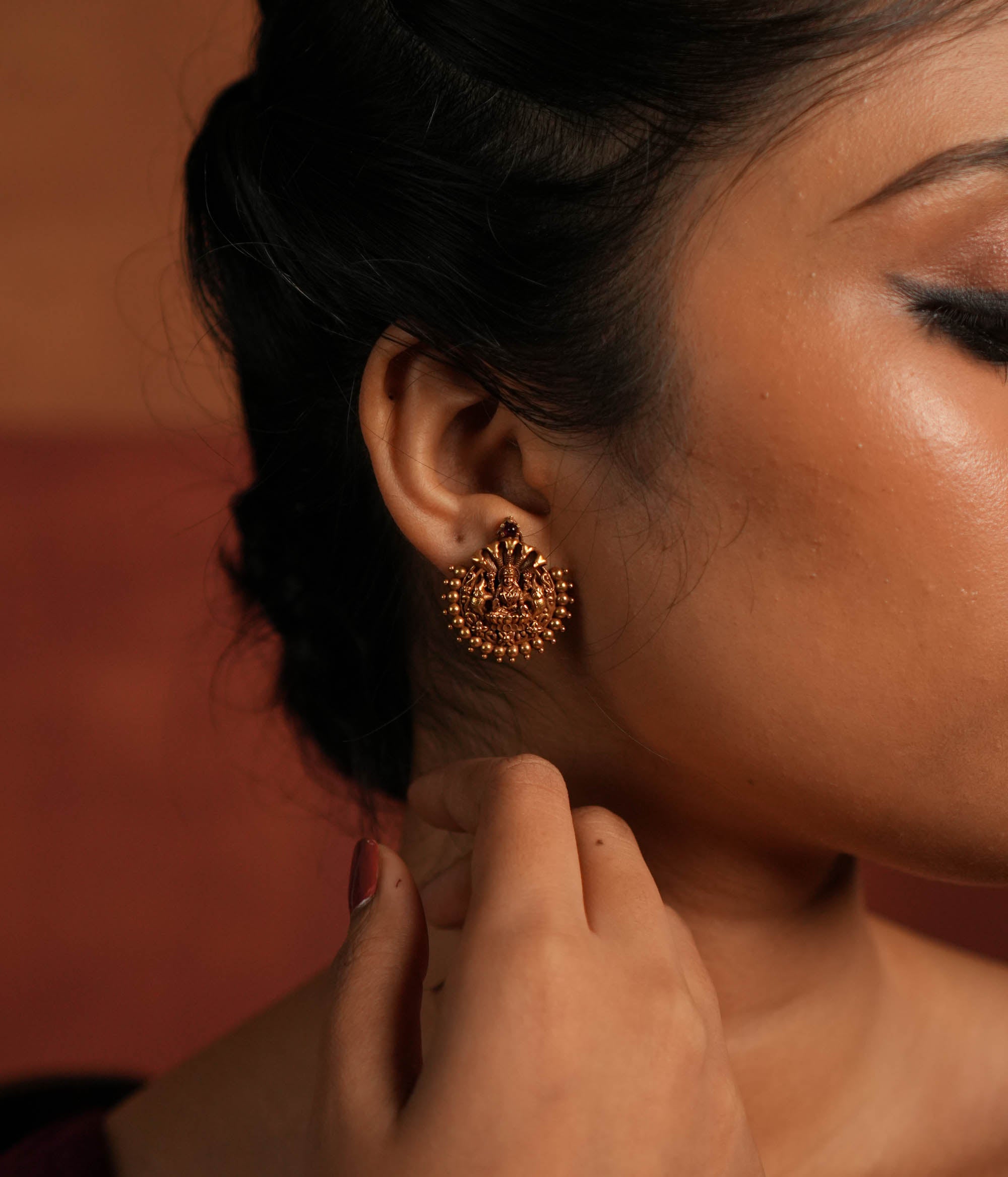 Divine elegance redefined! These gold-plated stud earrings feature Goddess Lakshmi, adorned with delicate golden beads. A perfect blend of tradition and modern charm.