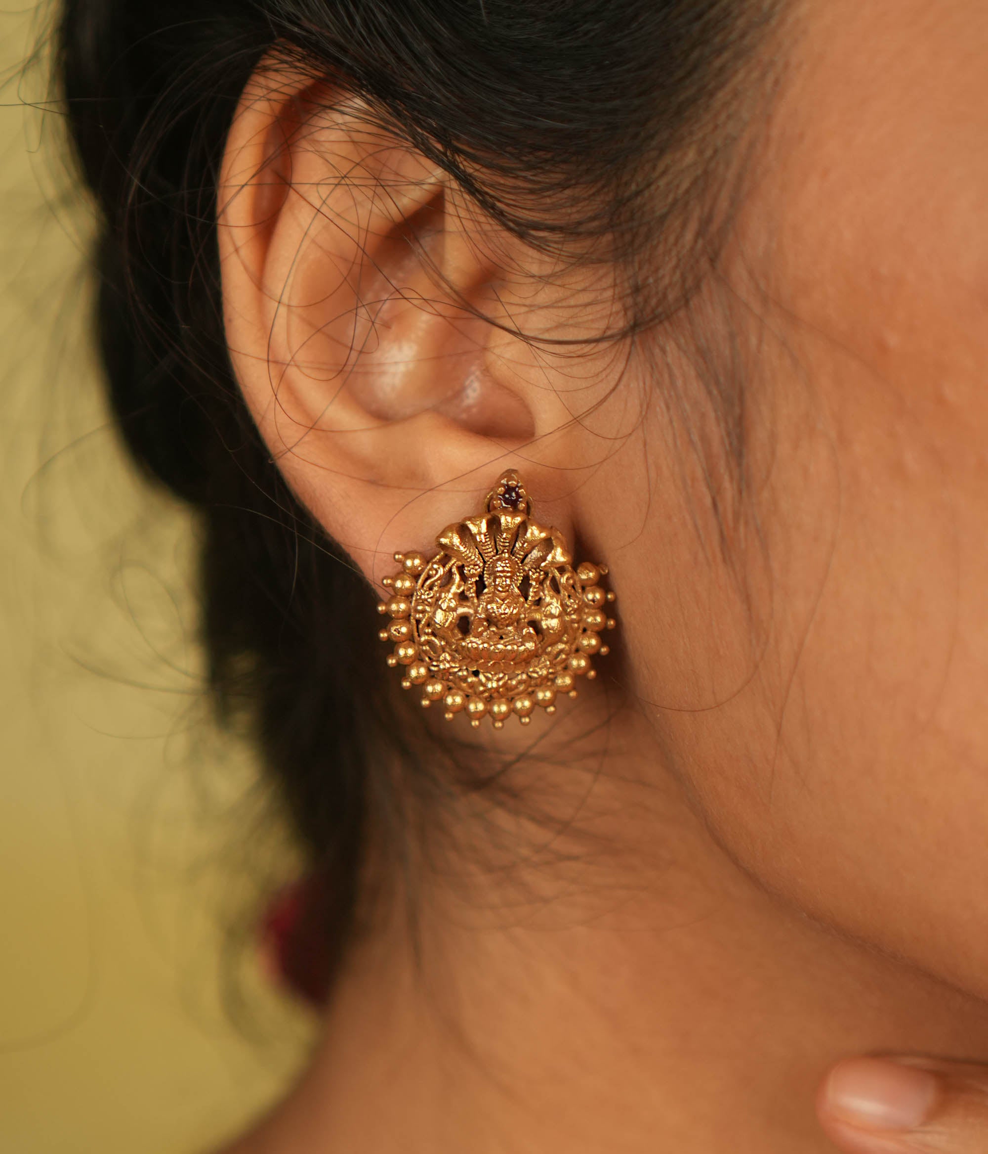 Divine elegance redefined! These gold-plated stud earrings feature Goddess Lakshmi, adorned with delicate golden beads. A perfect blend of tradition and modern charm.