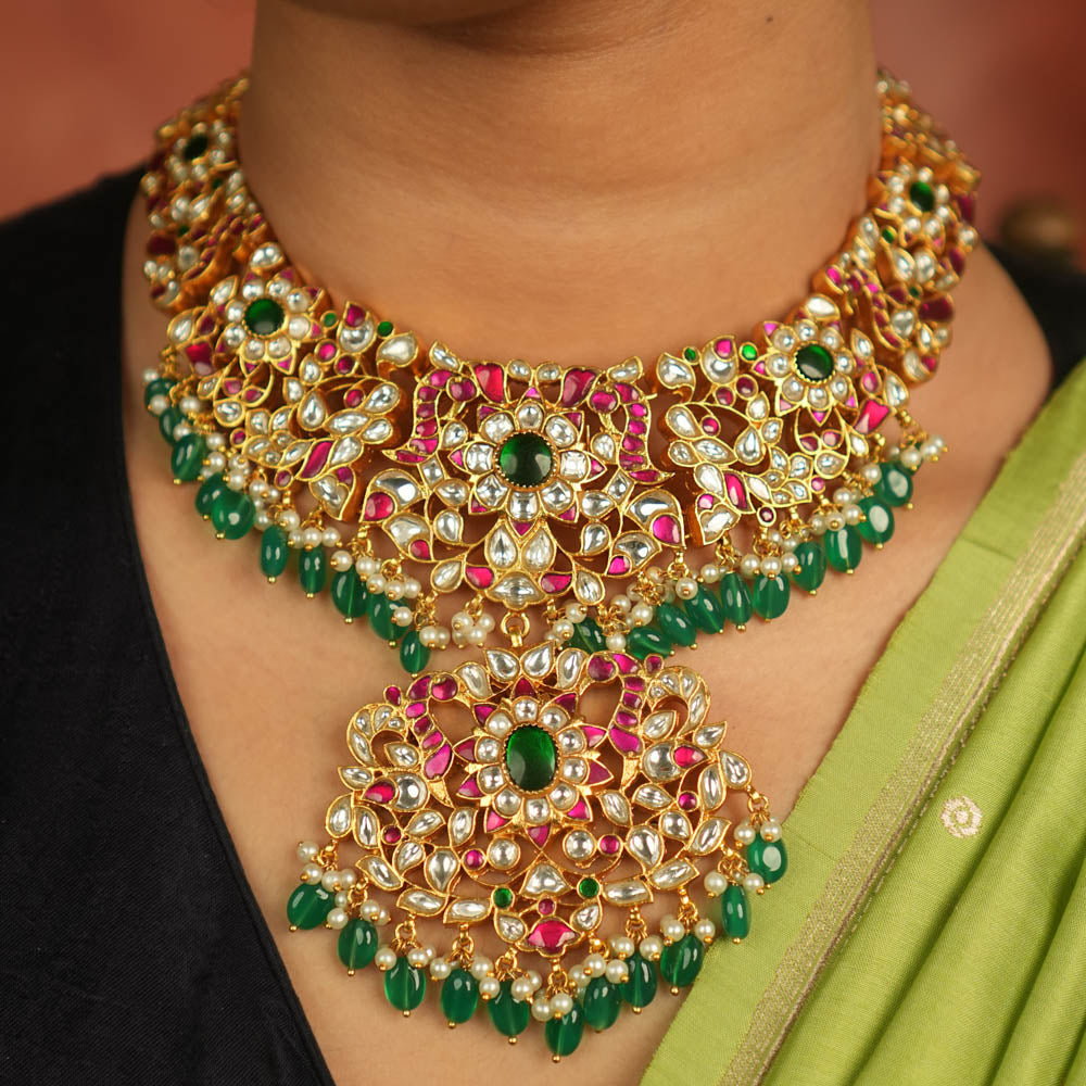 Temple whispers reborn! Antique gold necklace adorned with floral motifs, where kundan, pearls, and green beads evoke divine splendor and timeless elegance.