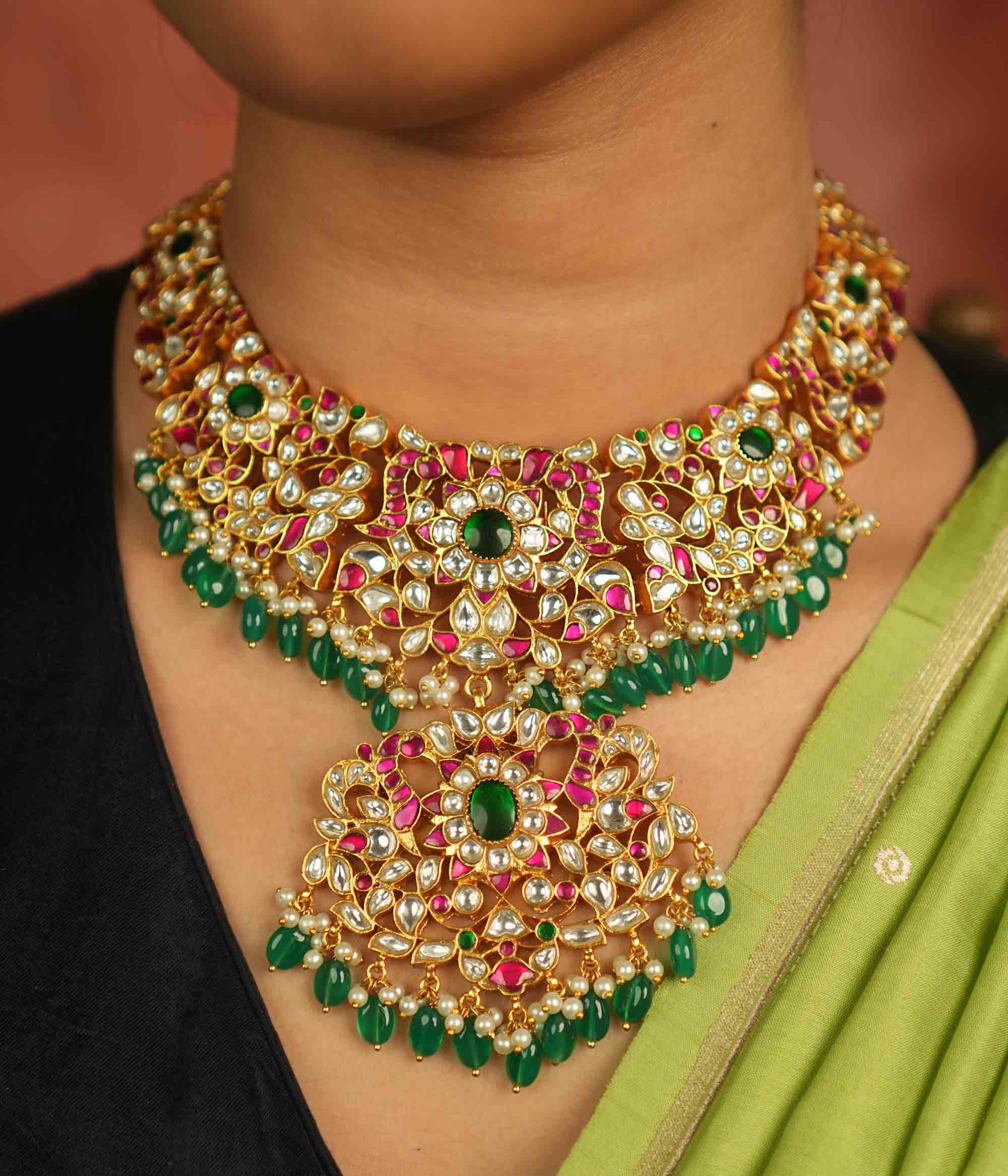 Temple whispers reborn! Antique gold necklace adorned with floral motifs, where kundan, pearls, and green beads evoke divine splendor and timeless elegance.