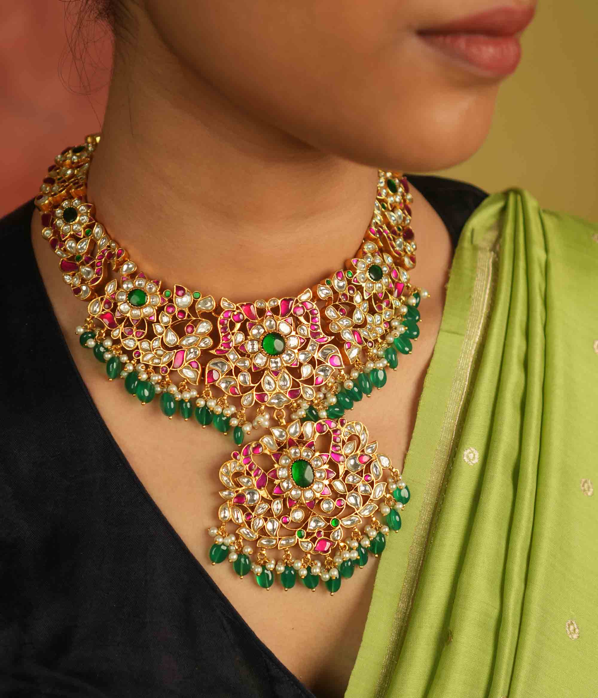 Temple whispers reborn! Antique gold necklace adorned with floral motifs, where kundan, pearls, and green beads evoke divine splendor and timeless elegance.