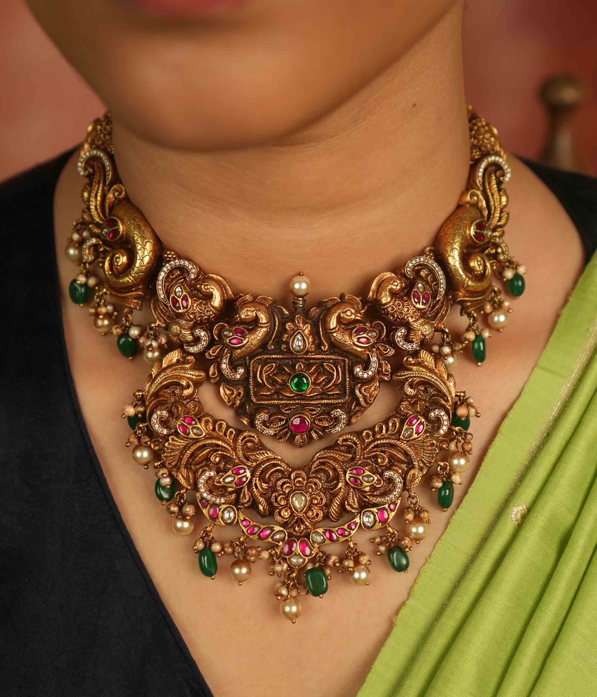 Temple whispers reborn! Antique gold necklace adorned with peacock and floral motifs, where kundan, pearls, and green beads evoke divine splendor and timeless elegance.