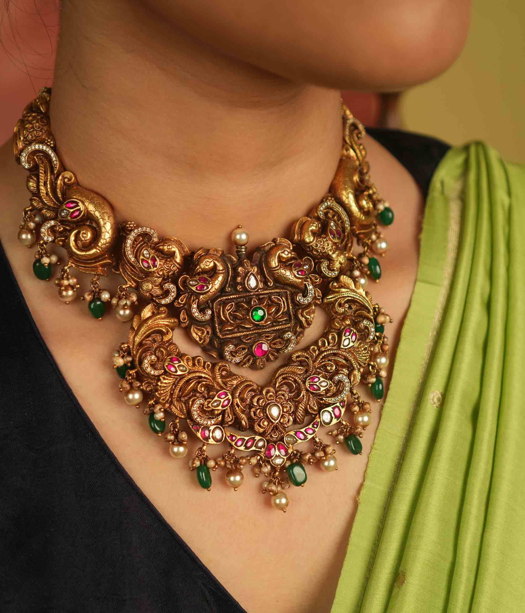 Temple whispers reborn! Antique gold necklace adorned with peacock and floral motifs, where kundan, pearls, and green beads evoke divine splendor and timeless elegance.