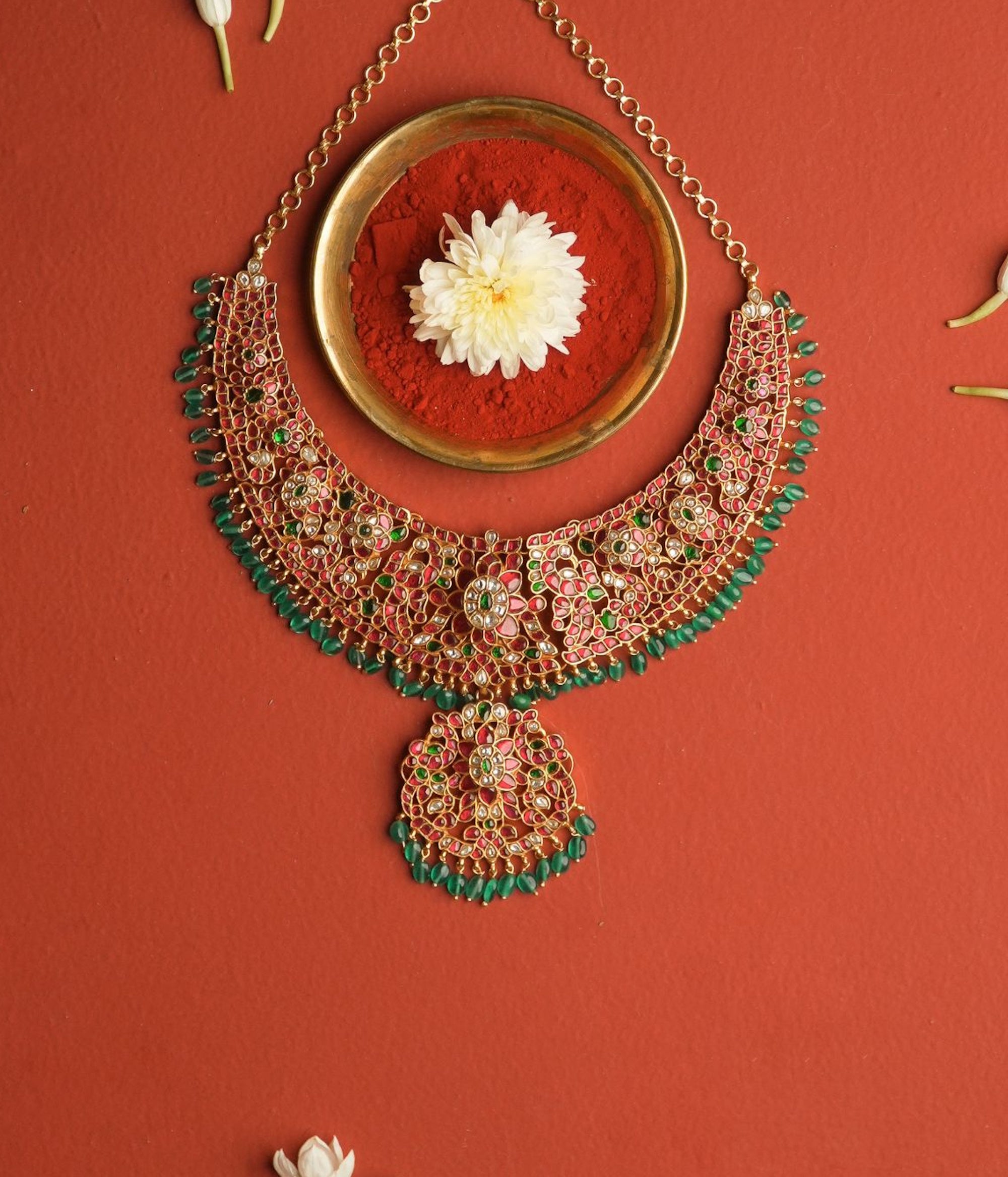 Ornate necklace with green and gold details on a red background