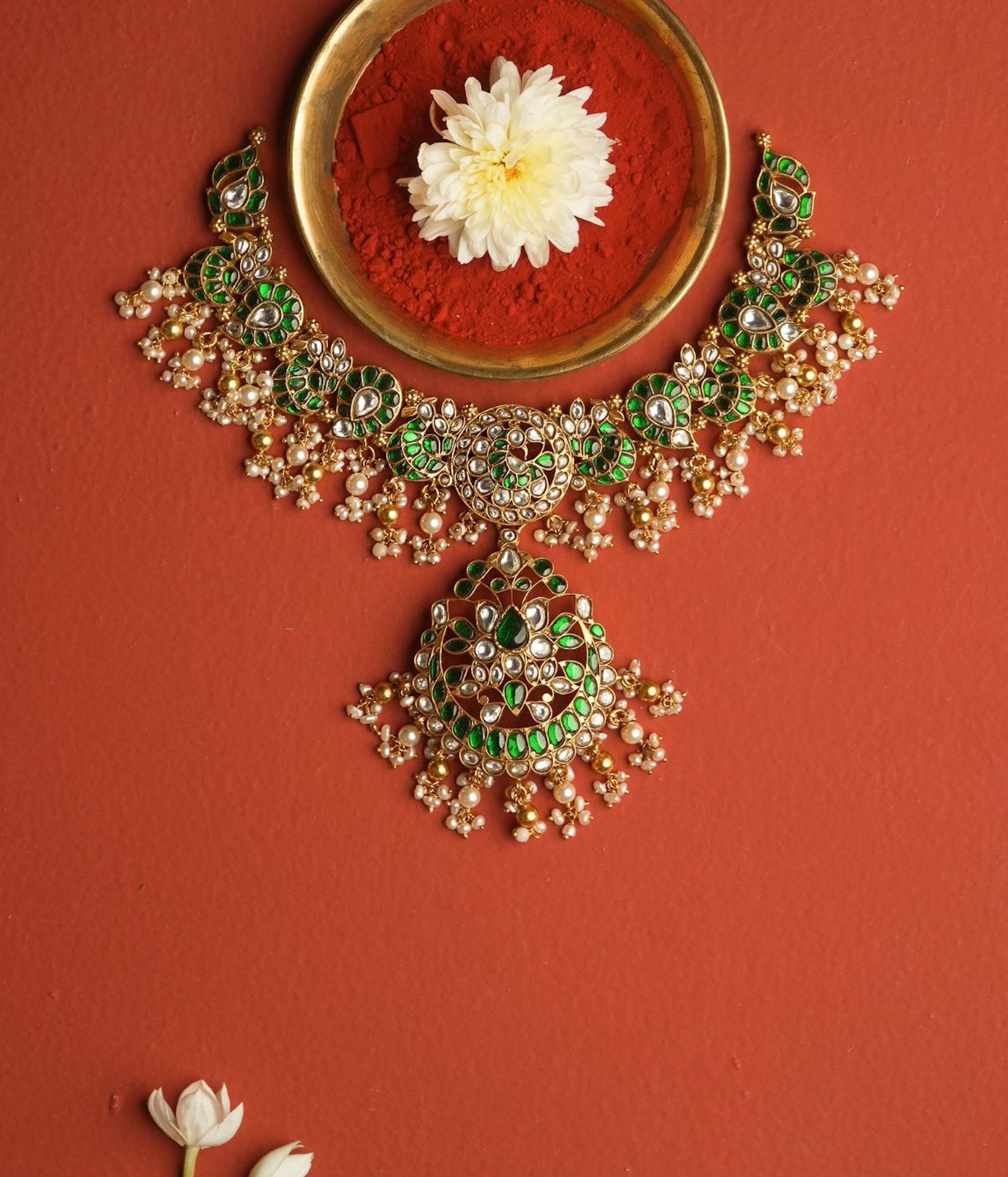 Ornate necklace with green and gold details on a red background