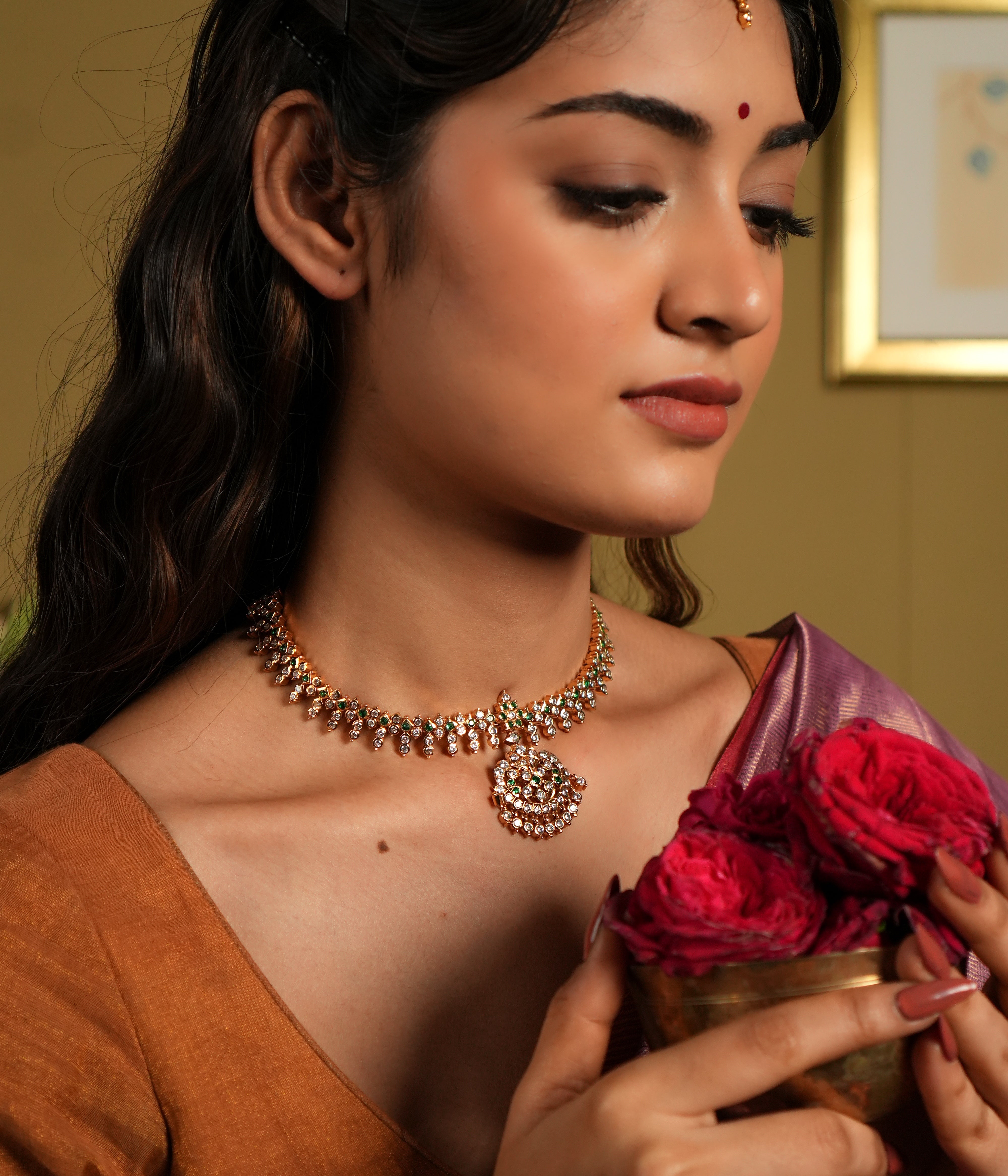 This exquisite Swarovski choker, crafted from 92.5 sterling silver with a rich 22-carat gold plating, is adorned with traditional floral motifs that whisper vintage Chettinad elegance. The intricate detailing and shimmering Swarovski stones bring a timeless charm, perfectly blending heritage craftsmanship with modern sophistication. Ideal for weddings and festive occasions, this choker gracefully accentuates your neckline, adding a touch of regal allure to any ensemble.